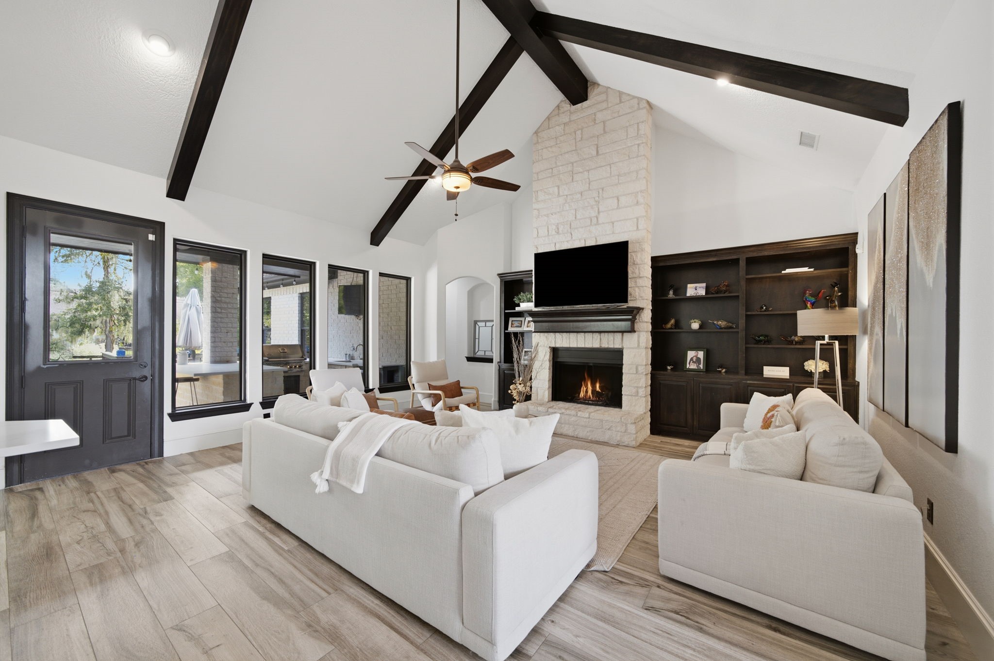 A soaring beamed cathedral ceiling and floor-to-ceiling stone fireplace create a striking focal point in the family room, while custom built-ins and expansive backyard views add warmth and character.