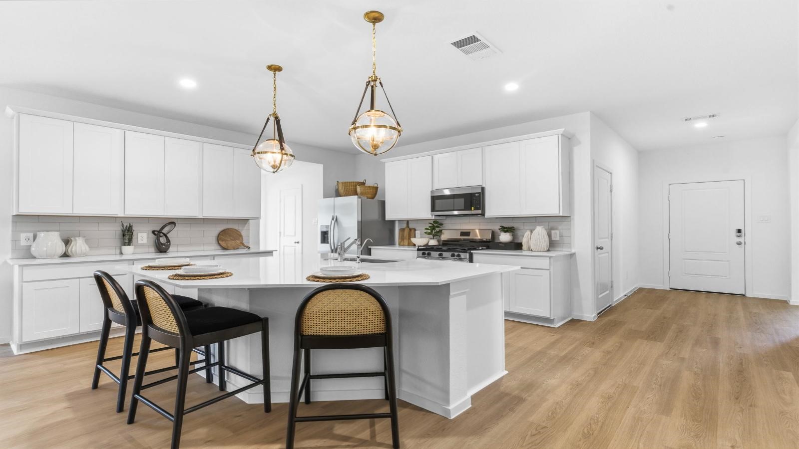 Bright and spacious kitchen with quartz countertops, stainless steel appliances, and an island with bar seating. Bright and spacious kitchen with quartz countertops, stainless steel appliances, and an island with bar seating.