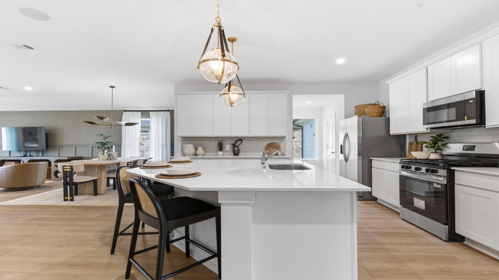 Bright and spacious kitchen with quartz countertops, stainless steel appliances, and an island with bar seating. Bright and spacious kitchen with quartz countertops, stainless steel appliances, and an island with bar seating.