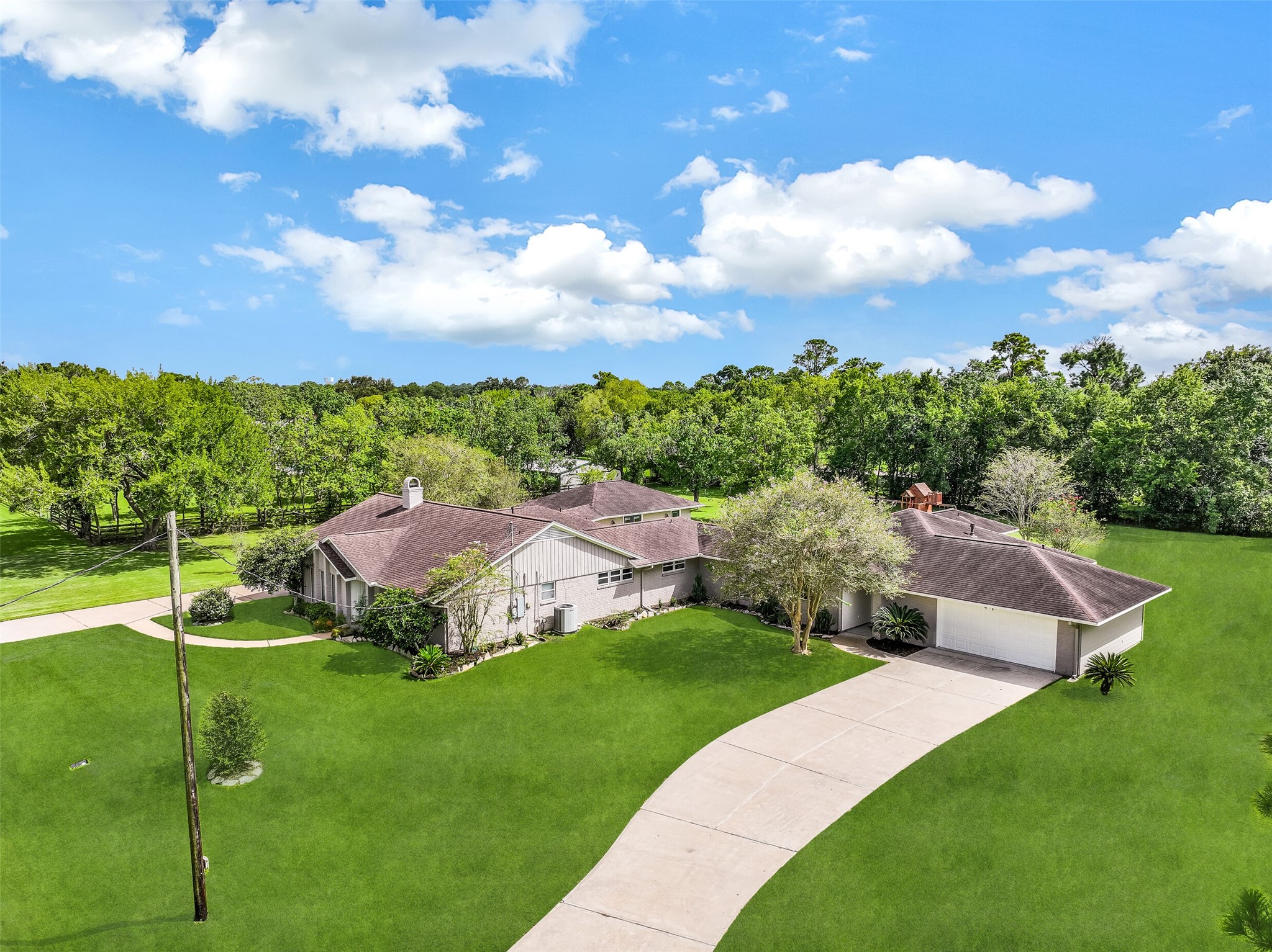Aerial View of Second Residence Side:
The second residence boasts a classic painted brick exterior with a covered entry, manicured landscaping, a long private driveway, & a 2-car attached garage, all positioned on a spacious 1.3-acre lot.