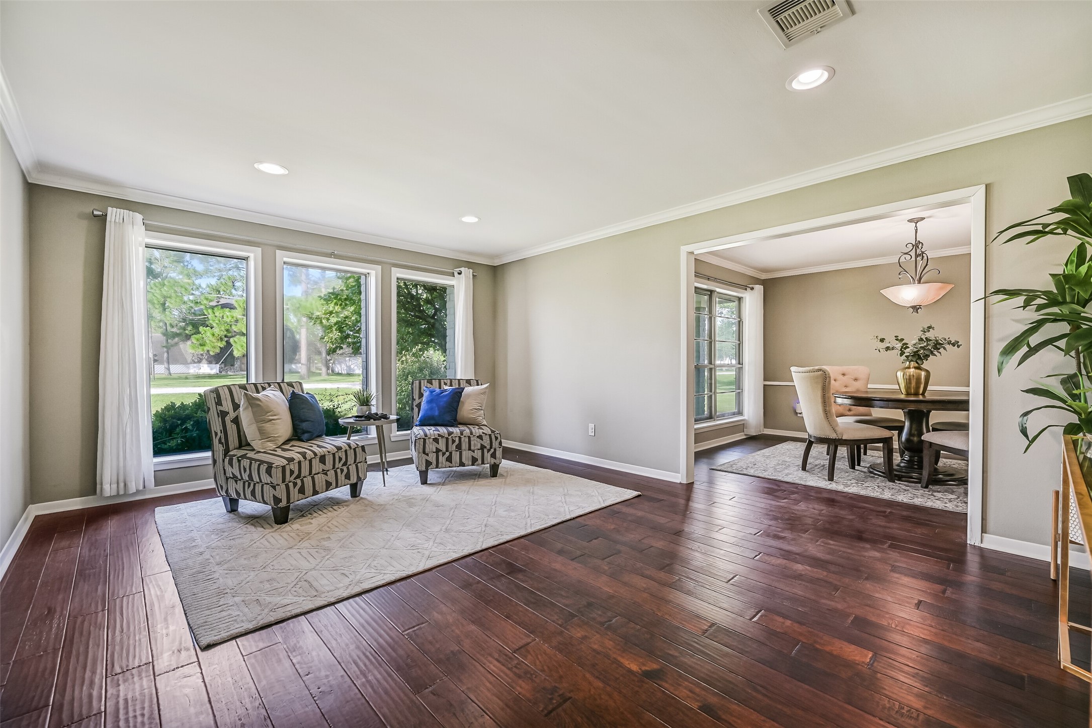 Formal Living & Dining  First Residence:
Gather in the formal living room just off the foyer with wood flooring, crown molding, and large windows for natural light, opening seamlessly into the formal dining room for effortless entertaining.