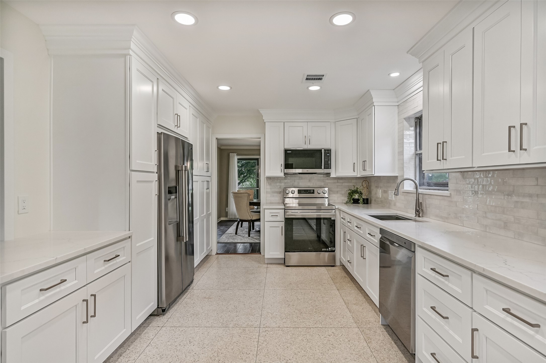 Kitchen  First Residence:
Moving into the masterfully remodeled kitchen in the first residence, note the  crisp, white quartz countertops, marble tile backsplash, all new stainless appliances, and ample new white cabientry offering an abundance of storage space.