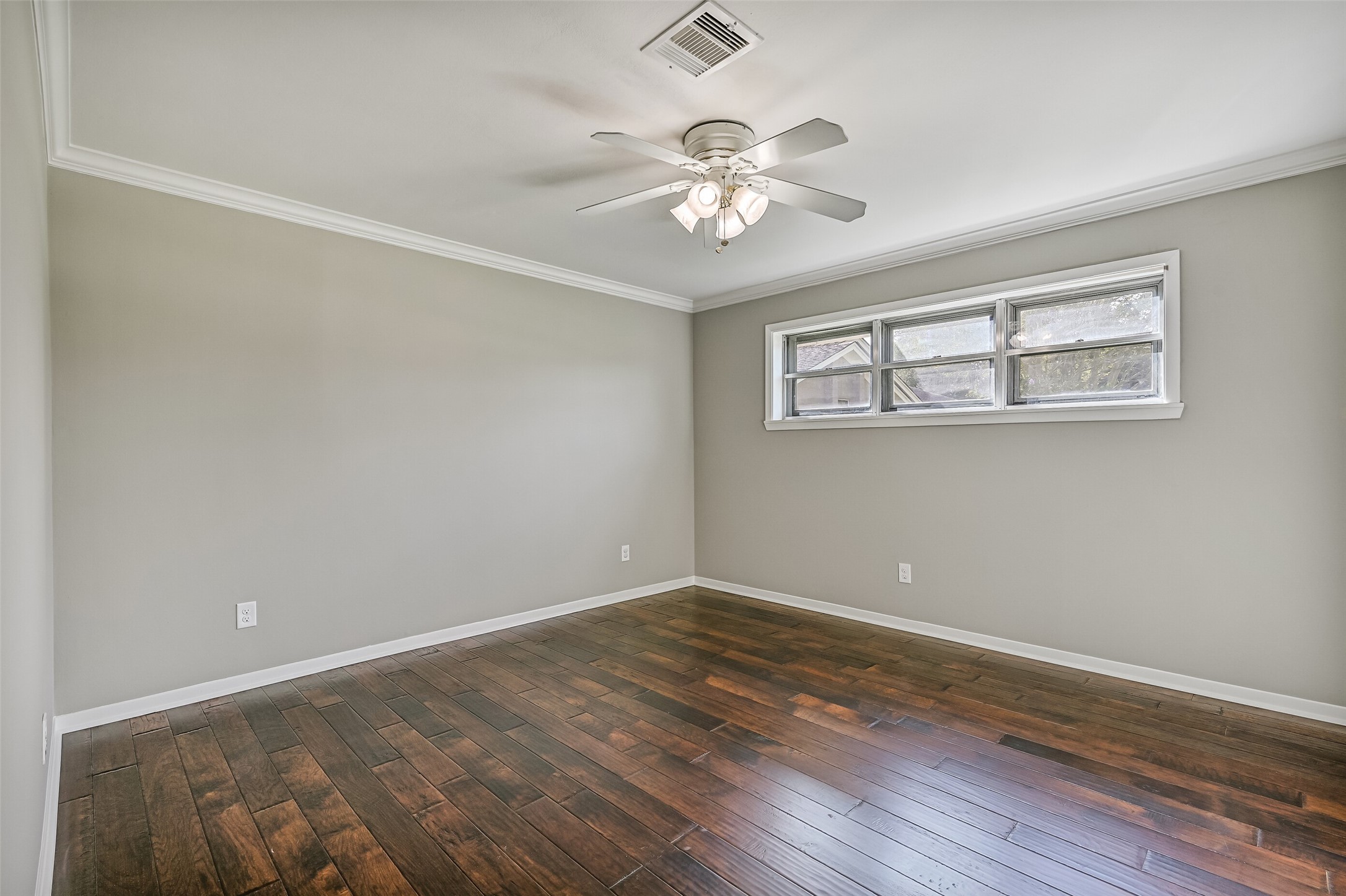 Bedroom 2  First Residence:
Another secondary bedroom boasts handsome wood flooring, neutral paint trimmed with crown molding, a lighted ceiling fan, two double-door closets, and windows providing natural light.