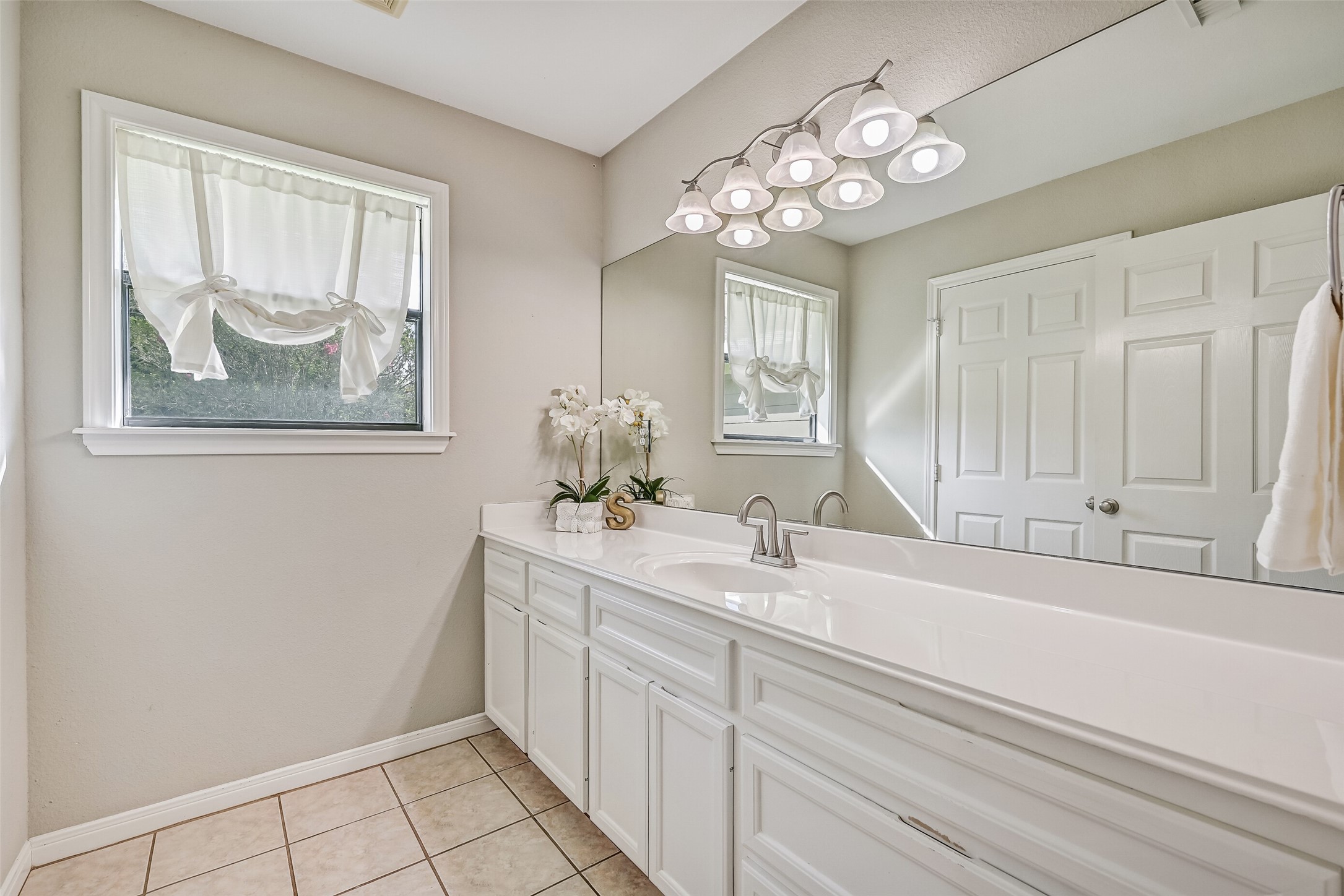 Guest Bathroom  Second Residence:
The guest bath offers an extended cultured marble vanity with ample storage, a wide mirror, and bright overhead lighting. The tub/shower combination offers easy access, while neutral finishes, tile flooring, and a window providing natural light create a clean, comfortable space.