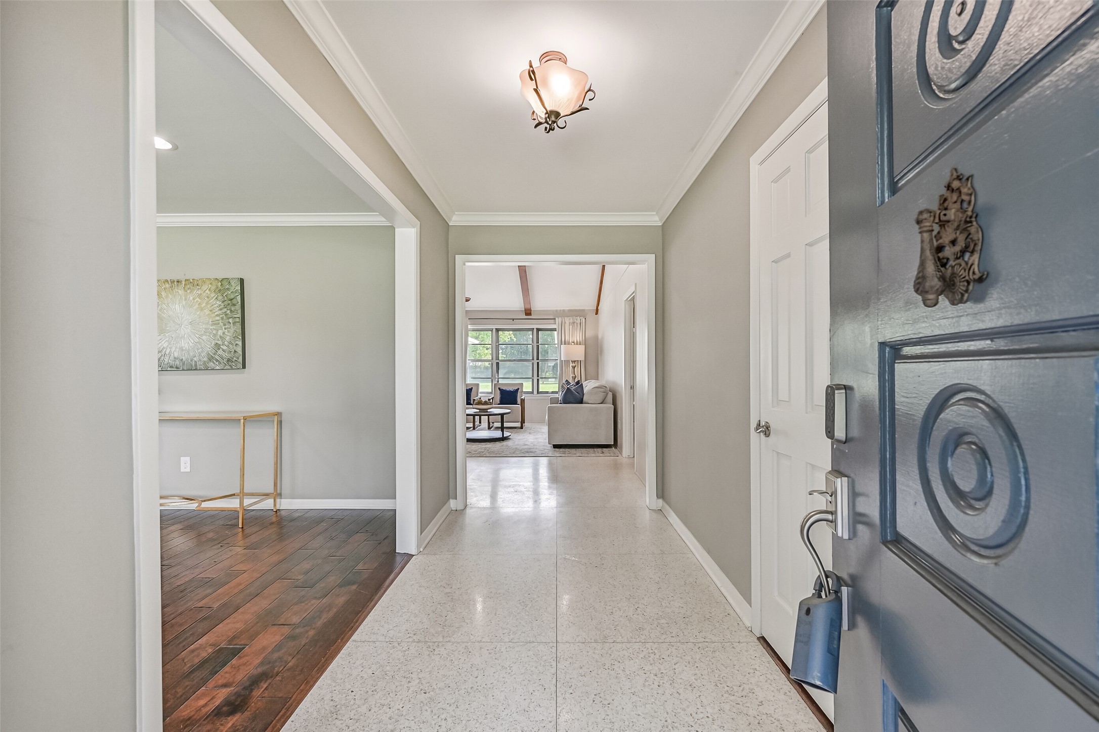 Foyer  First Residence:
Step through the inviting entry of the first home to experience clean sightlines into the light and bright living areas, finished with crown molding and a blend of terrazzo tile and wood flooring.