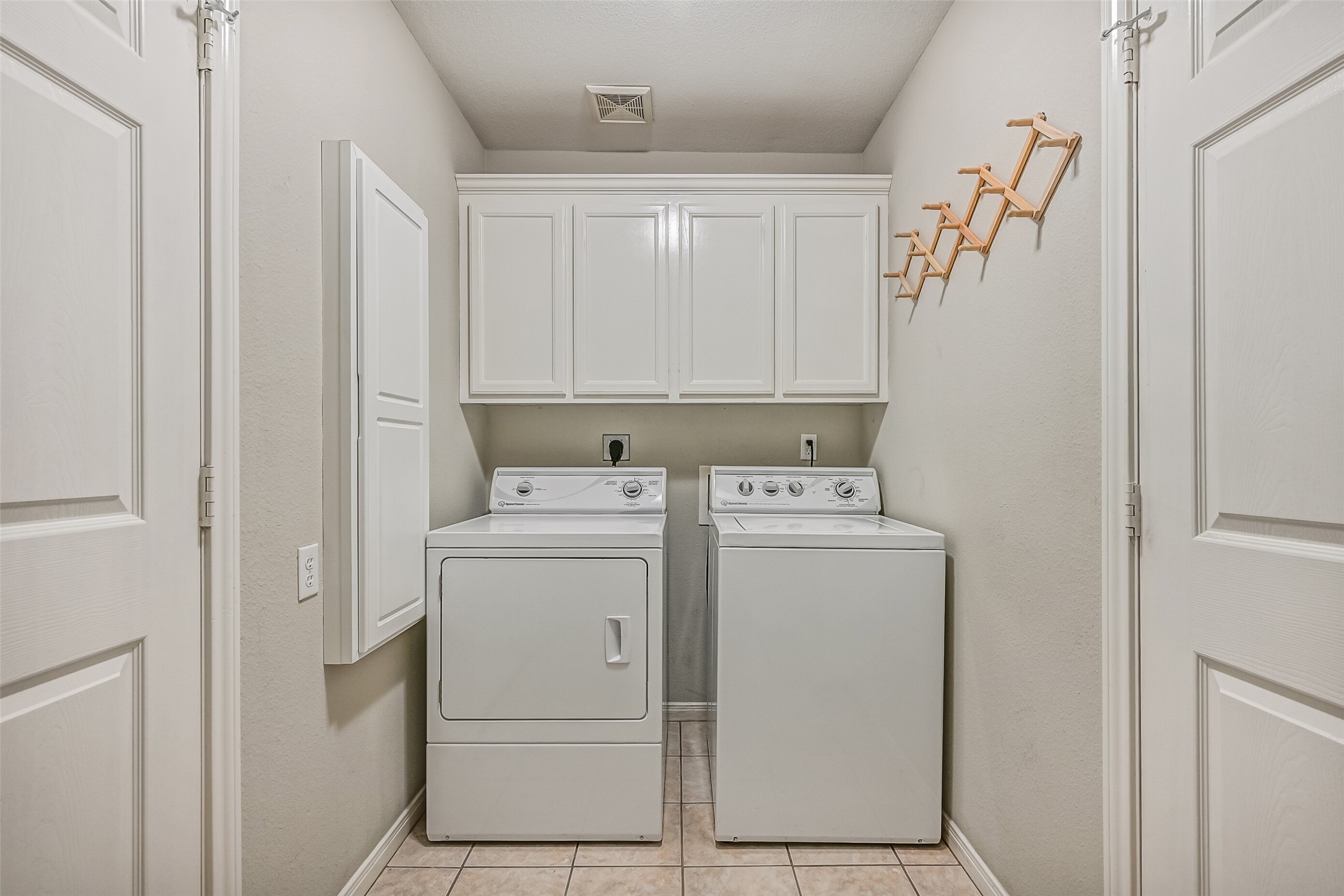 Utility Room  Second Residence:
A dedicated utility room boasts washer and dryer connections, overhead cabinetry, and a built-in ironing board for everyday convenience. A bonus storage closet adds extra functionality, and direct access to the attached two-car garage enhances ease of use and efficient daily flow.