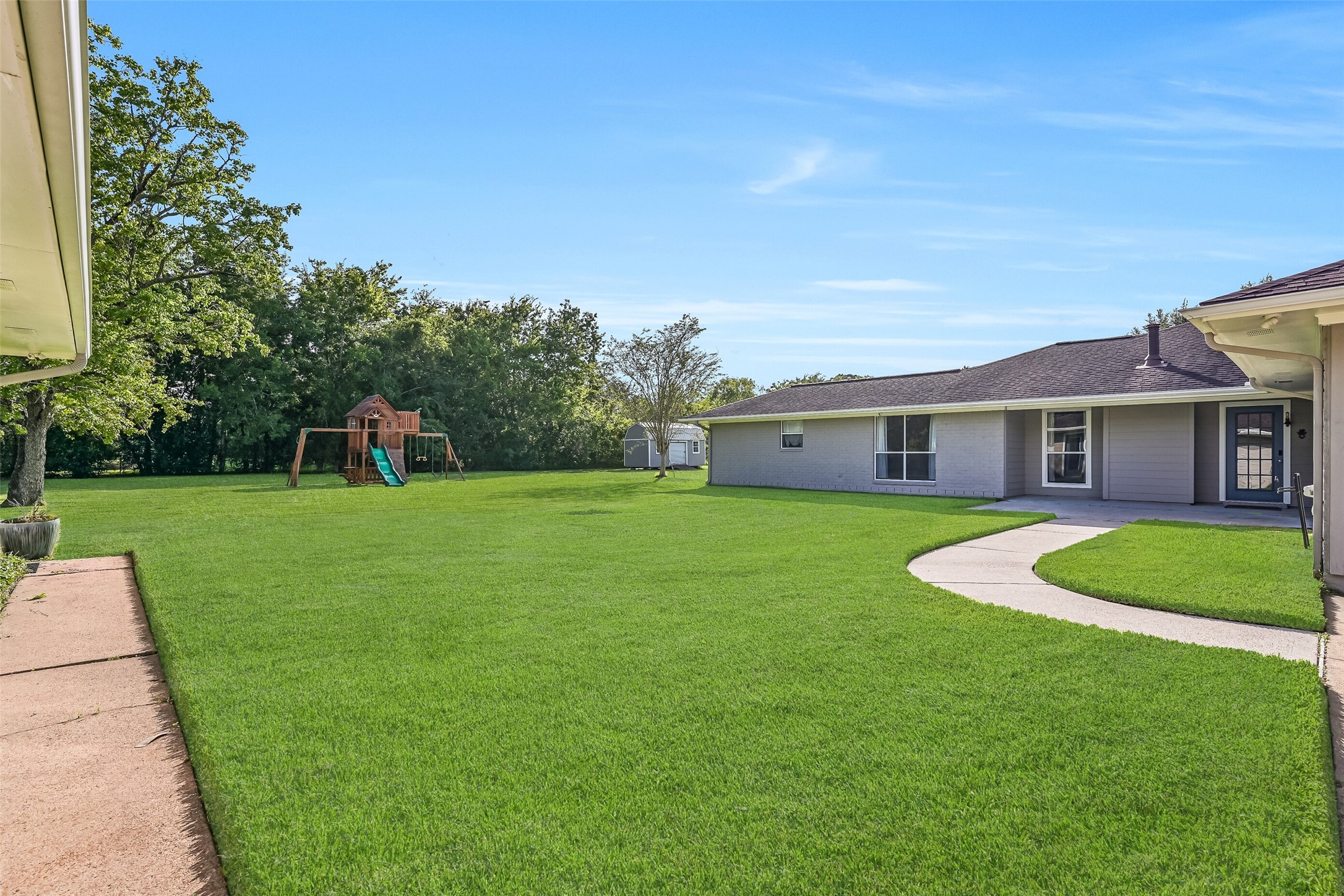 Stepping out the back door of the first residence, a concrete walkway provides access to the converted garage space, while a gently curved path leads to an additional concrete patio situated between the two residences.
