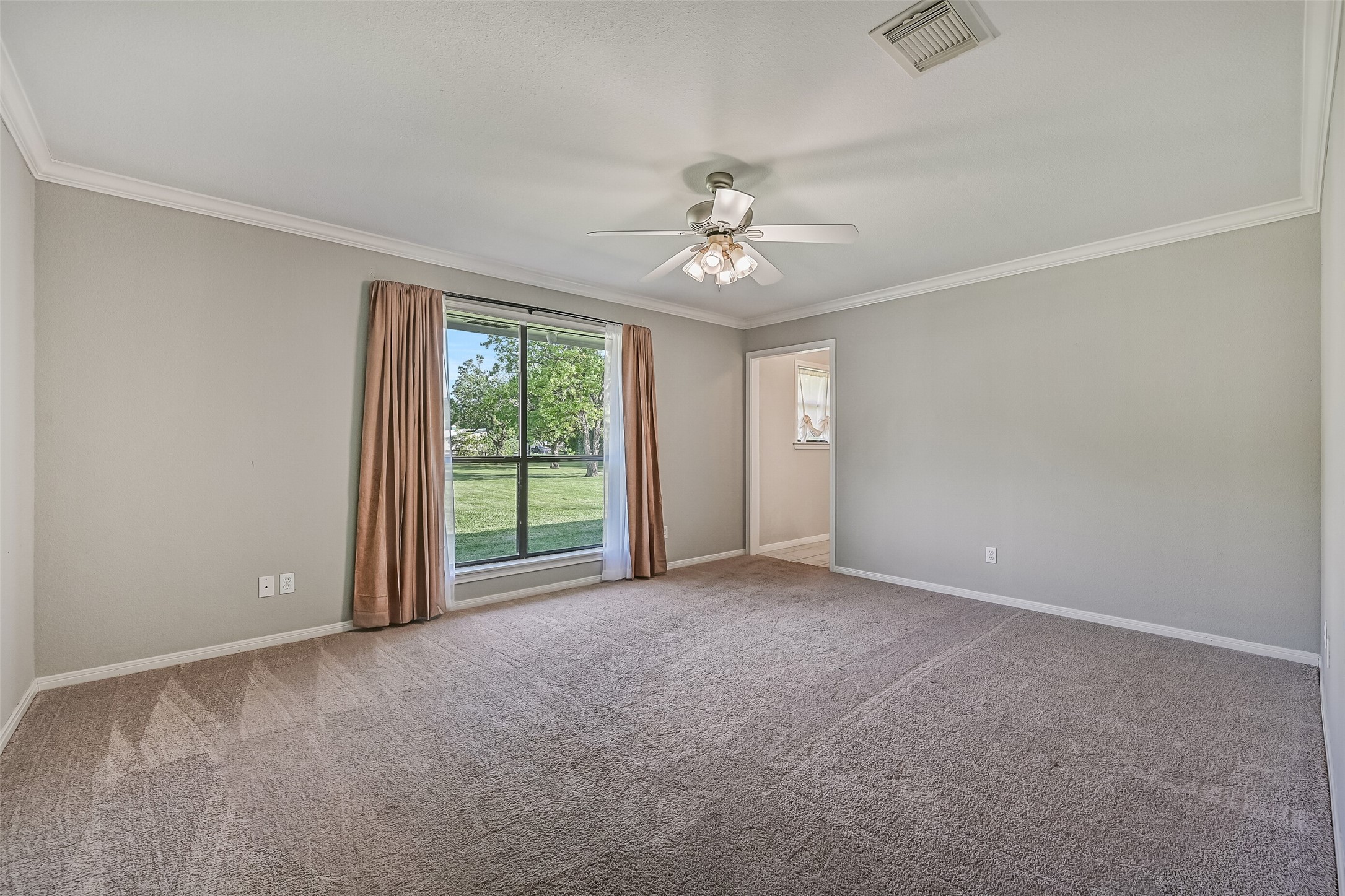 Owners Retreat  Second Residence:
The spacious primary bedroom showcases plush carpet, crown molding, and a lighted ceiling fan. Multiple side and rear-facing windows fill the room with soft natural light, creating a bright and restful retreat.