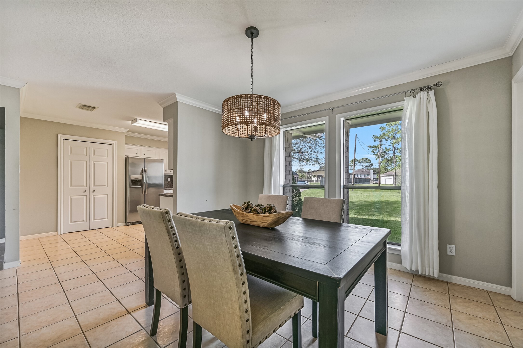 Dining Area  Second Residence:
An inviting dining area offers tile flooring, crown molding, and a statement chandelier. Conveniently positioned between the living area and kitchen, the step-free layout allows for easy movement and seamless flow.