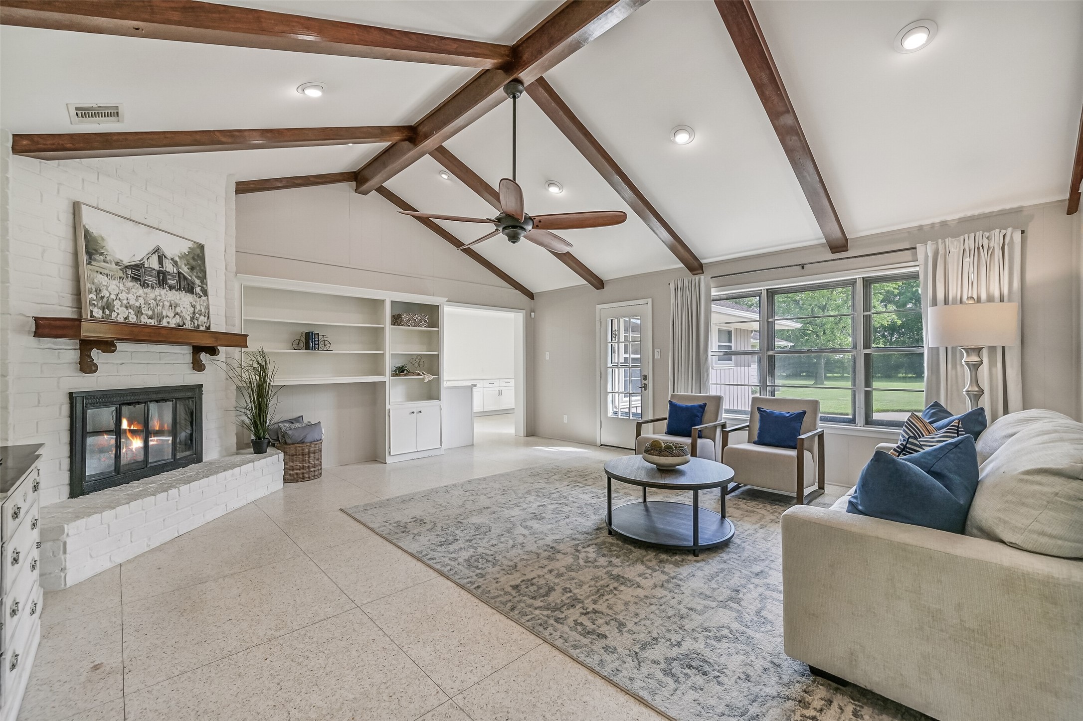 Family Room  First Residence:
Architectural built-in shelving anchors one wall, while a full wall of windows floods the family room with natural light and provides direct access to the concrete back patio. A wide entrance leads into the kitchen an breakfast room.