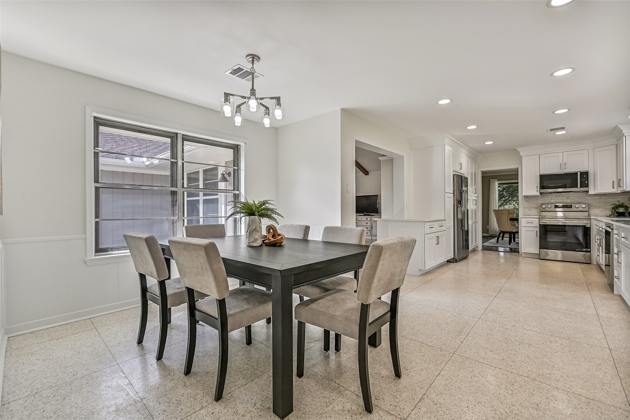 Breakfast Room  First Residence:
Terrazzo tile flows throughout the spacious breakfast room accented fresh paint and a modern chandelier, with large windows that fill the space with natural light and open sightlines into the kitchen and family room.