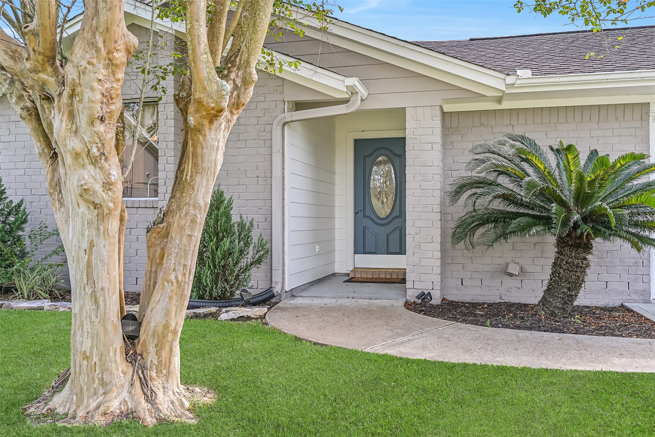 Front Porch  Second Residence:
A concrete path winds from the driveway of the second home to this covered front porch with a brick column, charming gabled rooflines, and a recessed entry, complemented by manicured landscaping.