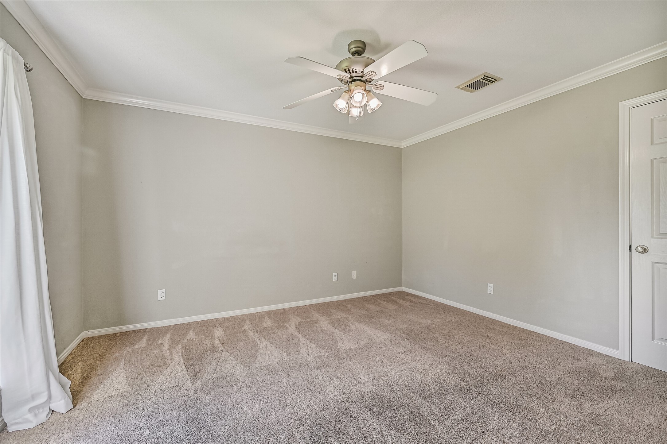Bedroom 1  Second Residence:
The first of two spacious secondary residence bedrooms features plush carpet, crown molding, and a lighted ceiling fan. A rear-facing window provides soft natural light and a peaceful view, while the walk-in closet offers generous storage.