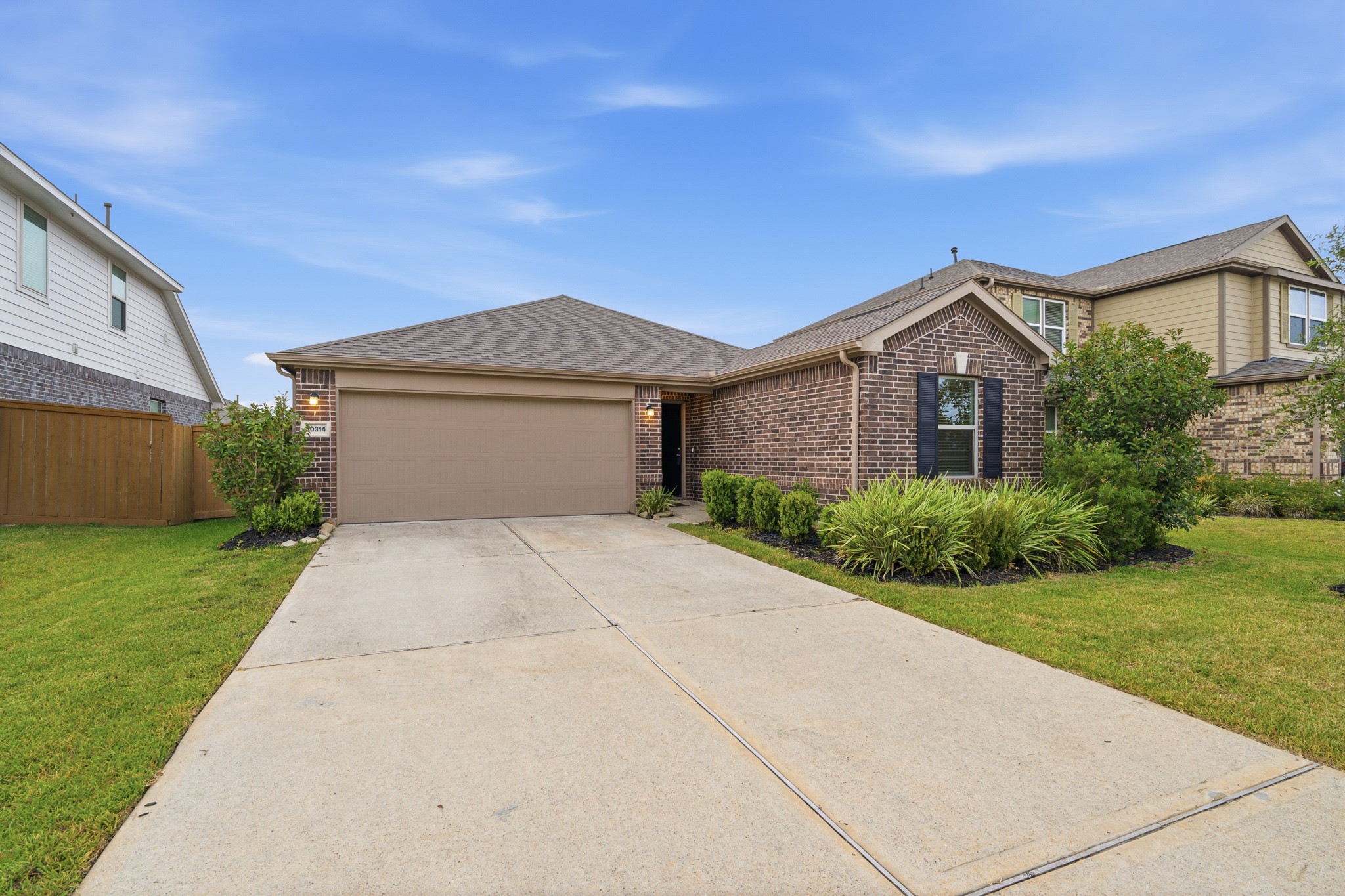 Charming brick home with a spacious driveway and manicured landscaping, offering a warm and inviting welcome.