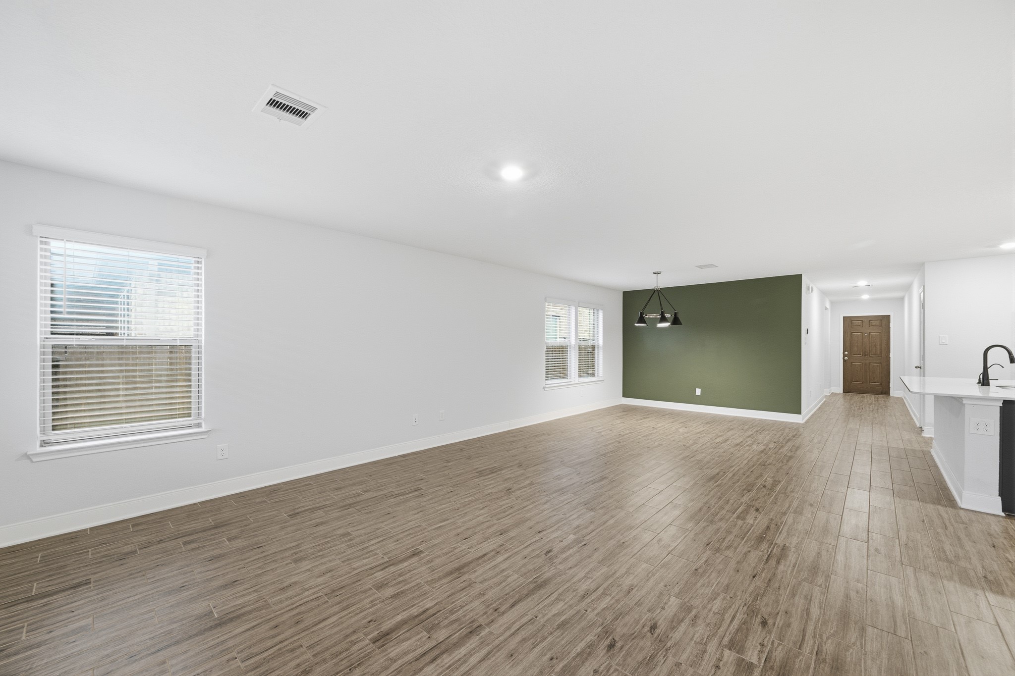 Spacious open-concept living and breakfast area with sleek flooring and a stylish accent wall, perfect for modern living and entertaining.