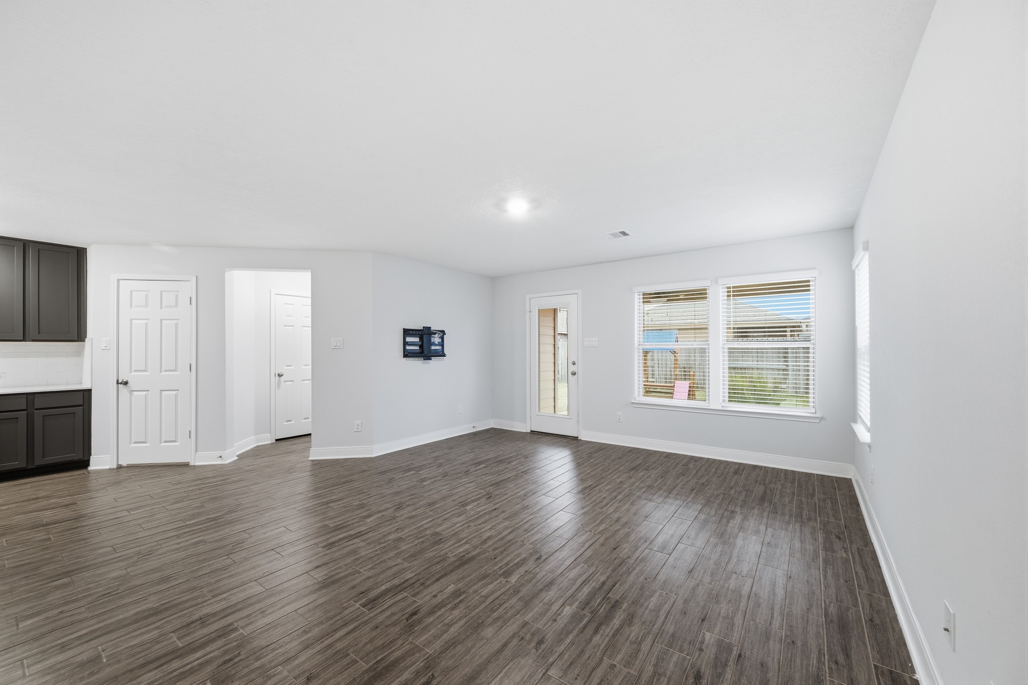 Spacious living area with sleek flooring, abundant natural light from large windows, and seamless access to the outdoor space through a glass door.
