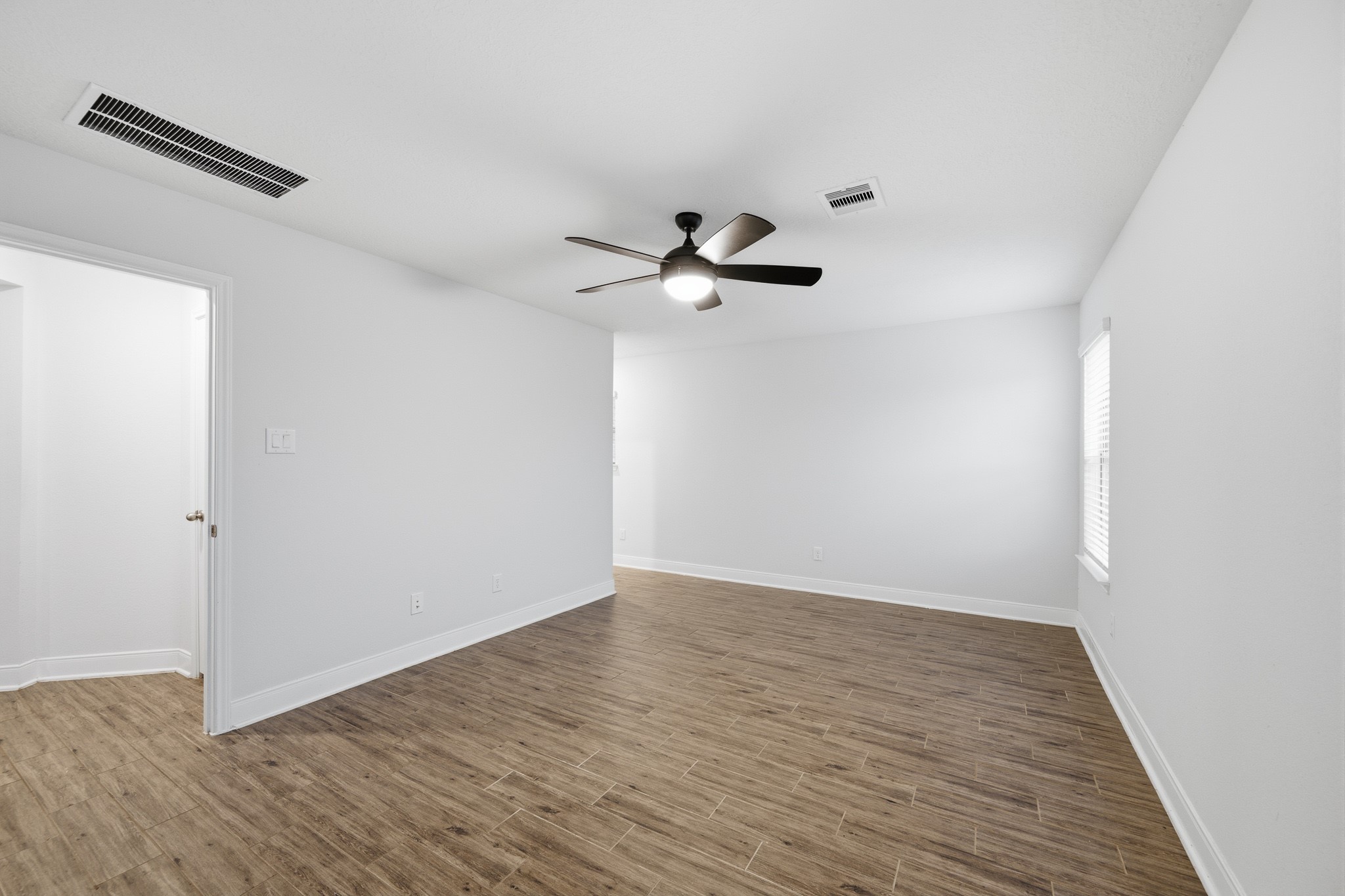 Bright and spacious room featuring sleek flooring, a modern ceiling fan.