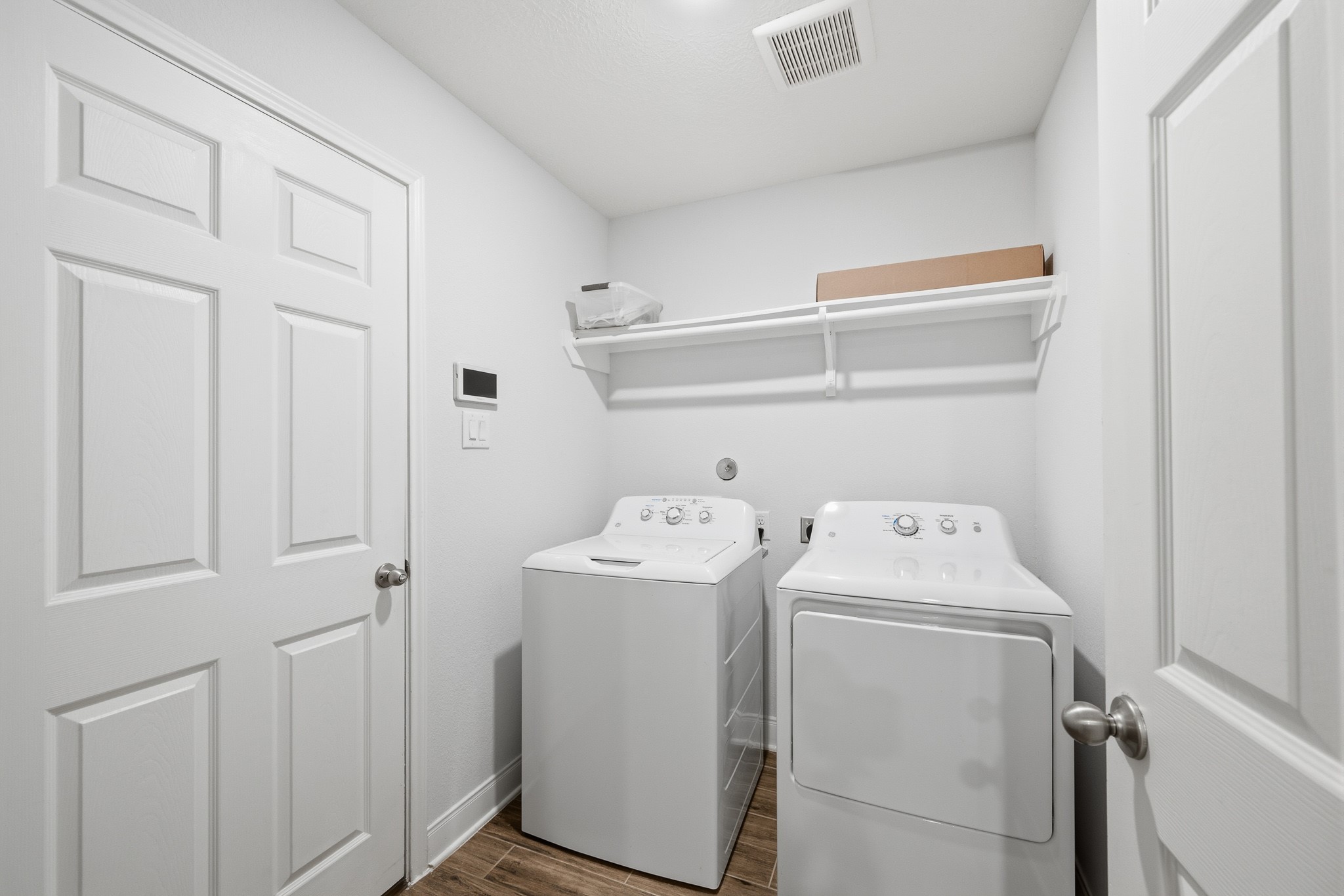Streamline your chores in this efficient utility room, featuring modern appliances and convenient shelving for all your laundry needs.