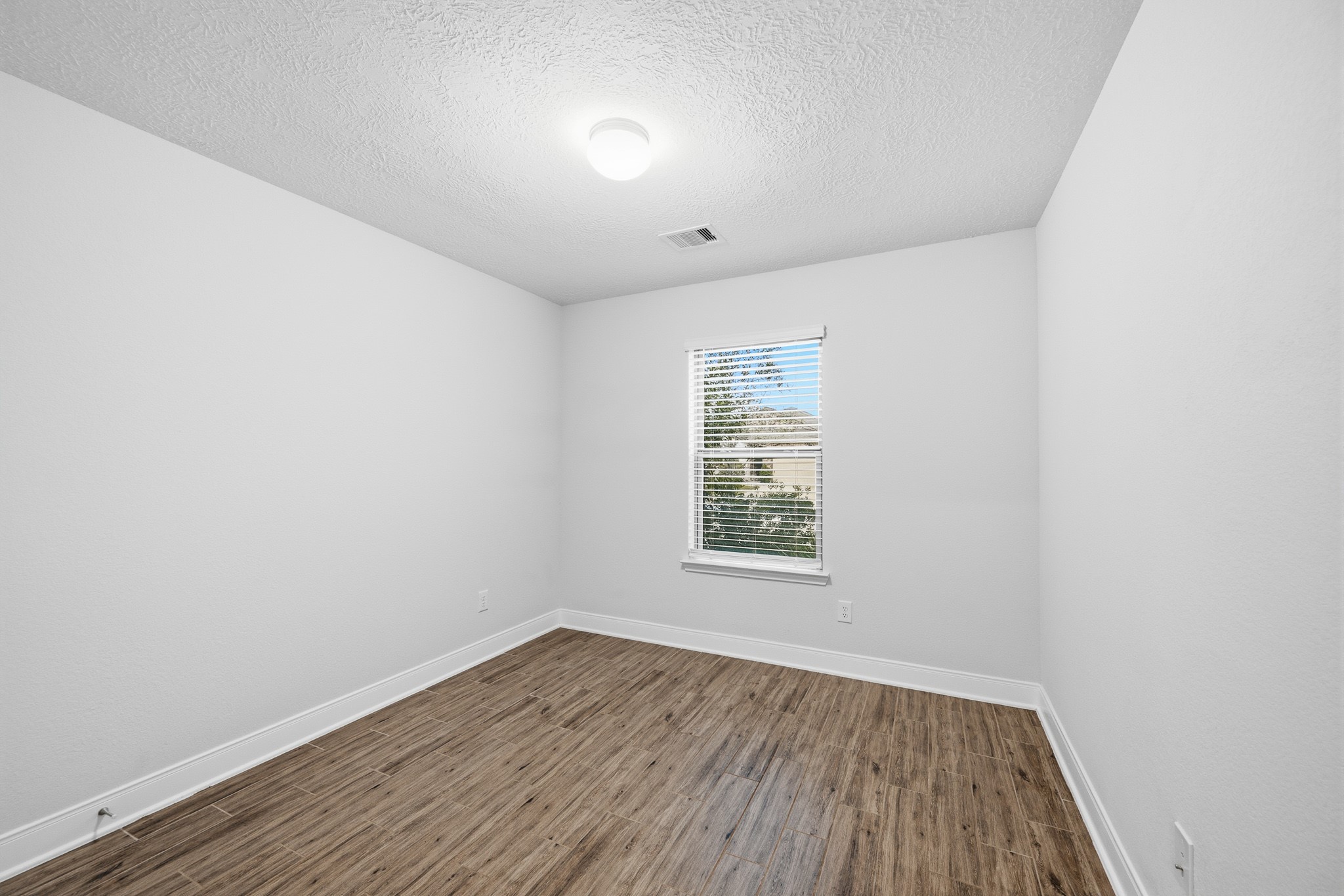 Bedroom 3 offers sleek flooring and crisp white walls, with a window for natural lighting.