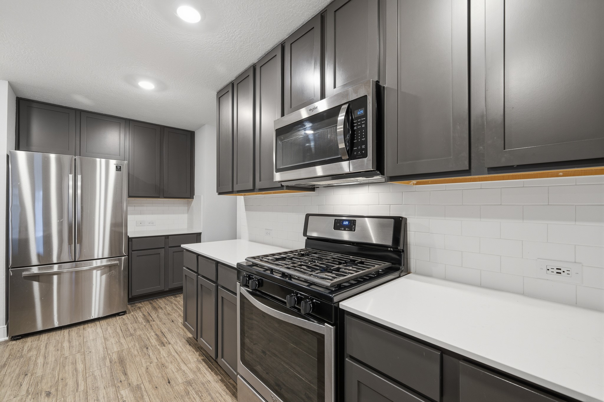 Sleek and modern kitchen featuring stainless steel appliances, elegant dark cabinetry, and a bright subway tile backsplash.