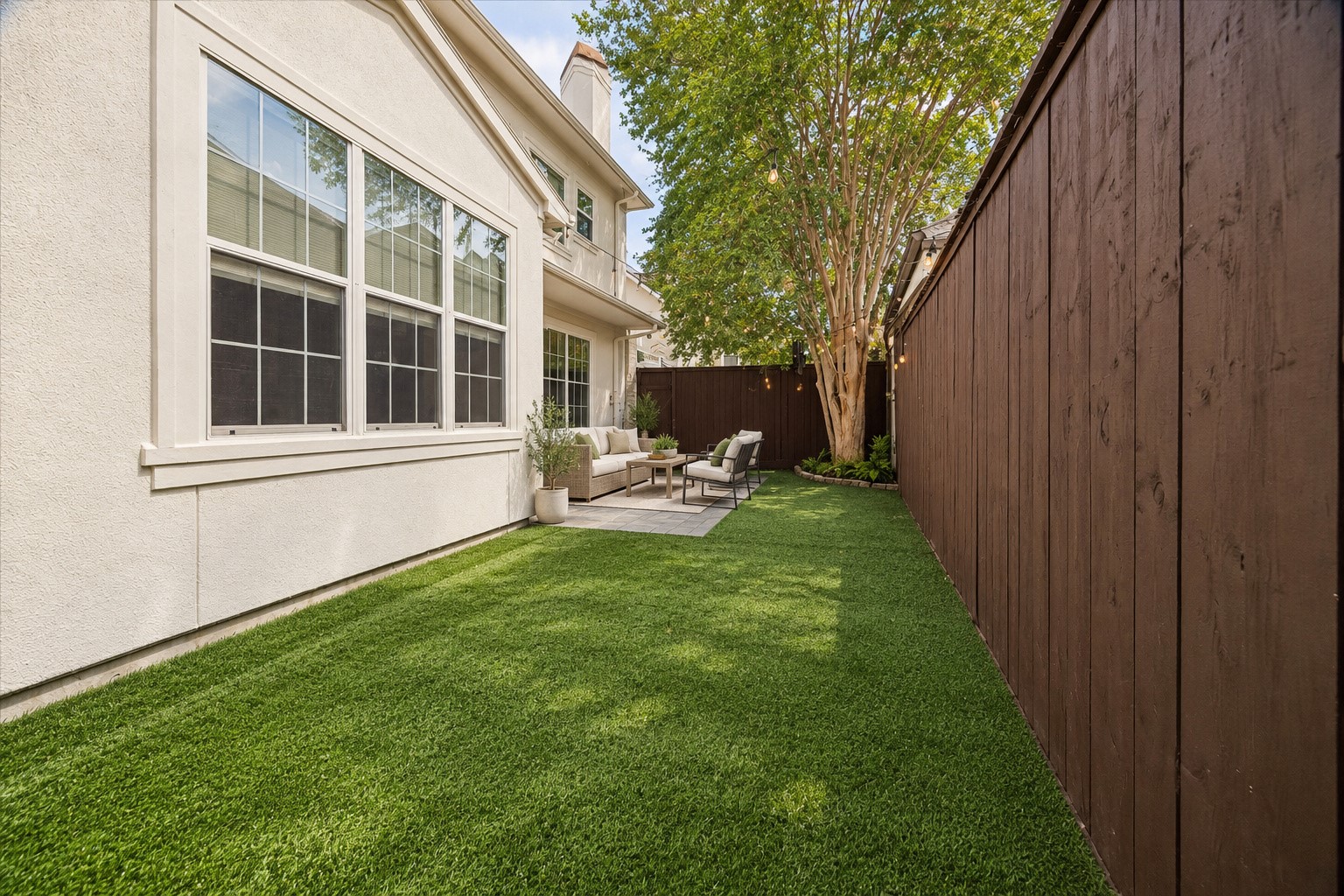 Beautiful view highlighting the turfed green space & mature tree providing shade. The fully fenced backyard offers plenty of room for kids & pets to play, while the patio provides a separate area for outdoor dining & entertaining. A fabulous low-maintenance outdoor retreat! (Photo virtually enhanced/furnishings virtually staged).