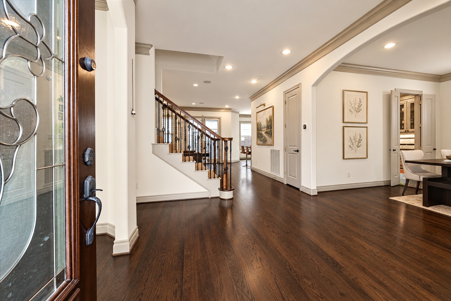 Upon entering, you are greeted by beautiful hardwood flooring, crown molding, recessed lighting & welcoming entry w/ decorative glass front door. Arched walkways lead to formal living on the let & dining space on the right, while entry hall continues toward family room & kitchen. Notice the generous wall space, offering the perfect place for a console table & artwork. Wall art virtually staged.