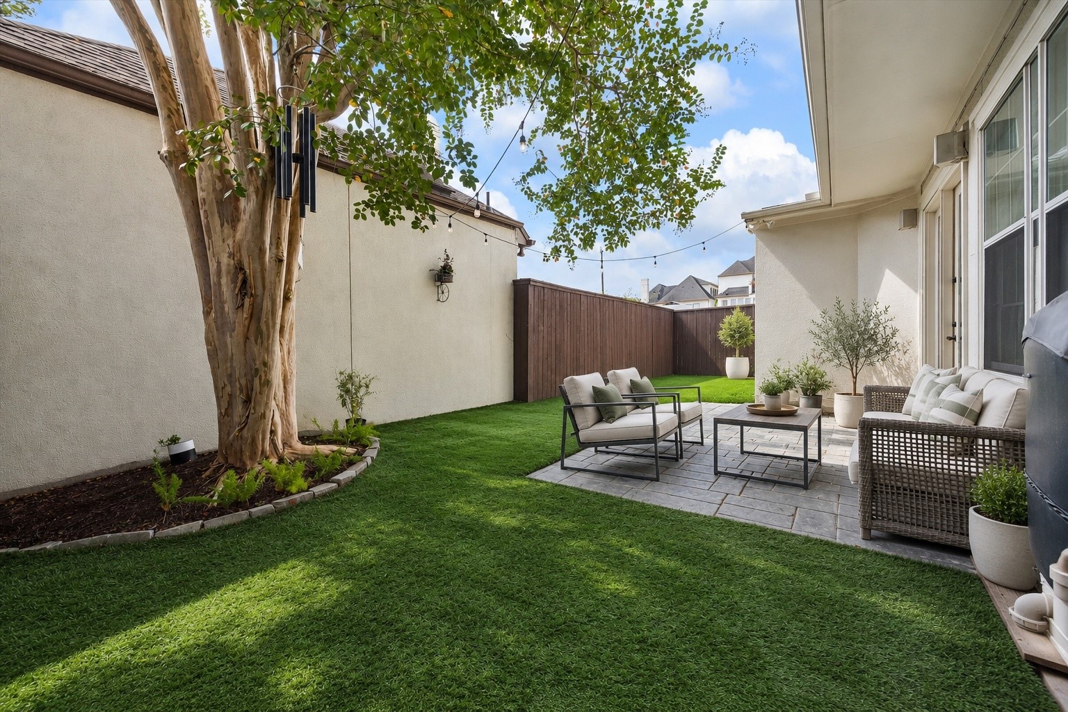 A sneak peak of the wonderful private backyard offering a lovely extension of the home's living spaces! Spacious patio provides ample room for outdoor furnishings & entertaining, while low-maintenance turfed green space creates a beautiful setting for pets, play & everyday enjoyment. Fully fenced w/ mature landscaping providing shade. (Photo virtually enhanced/furnishings virtually staged).