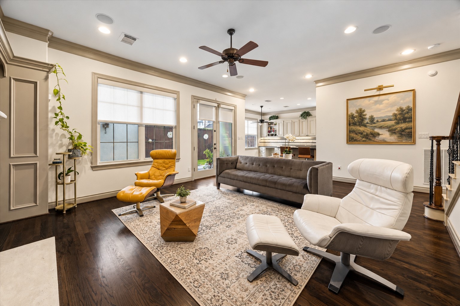 Another perspective of the spacious family room highlighting the thoughtful connection to kitchen & breakfast area. Open floor plan creates a seamless flow between main living spaces, ideal for everyday living & entertaining. French doors w/ Hunter Douglas shades lead directly to backyard patio, providing a wonderful extension of the living space. Virtually staged.