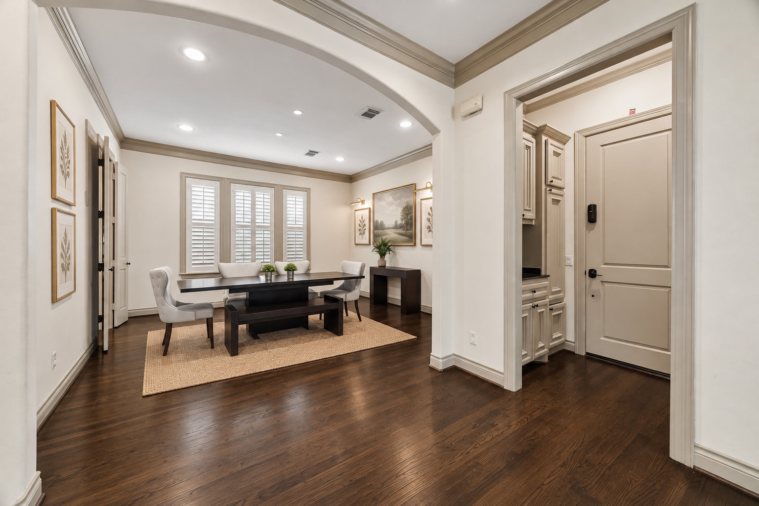 Beautiful view showcasing the thoughtful layout of the home's 1st floor. Welcoming entry opens to formal dining room on the left & provides convenient access to adjacent drop zone leading to attached garage on the right. Hardwood flooring, crown molding, recessed lighting & arched walkways continue throughout the main living spaces, creating a wonderful flow for everyday living. Virtually staged.