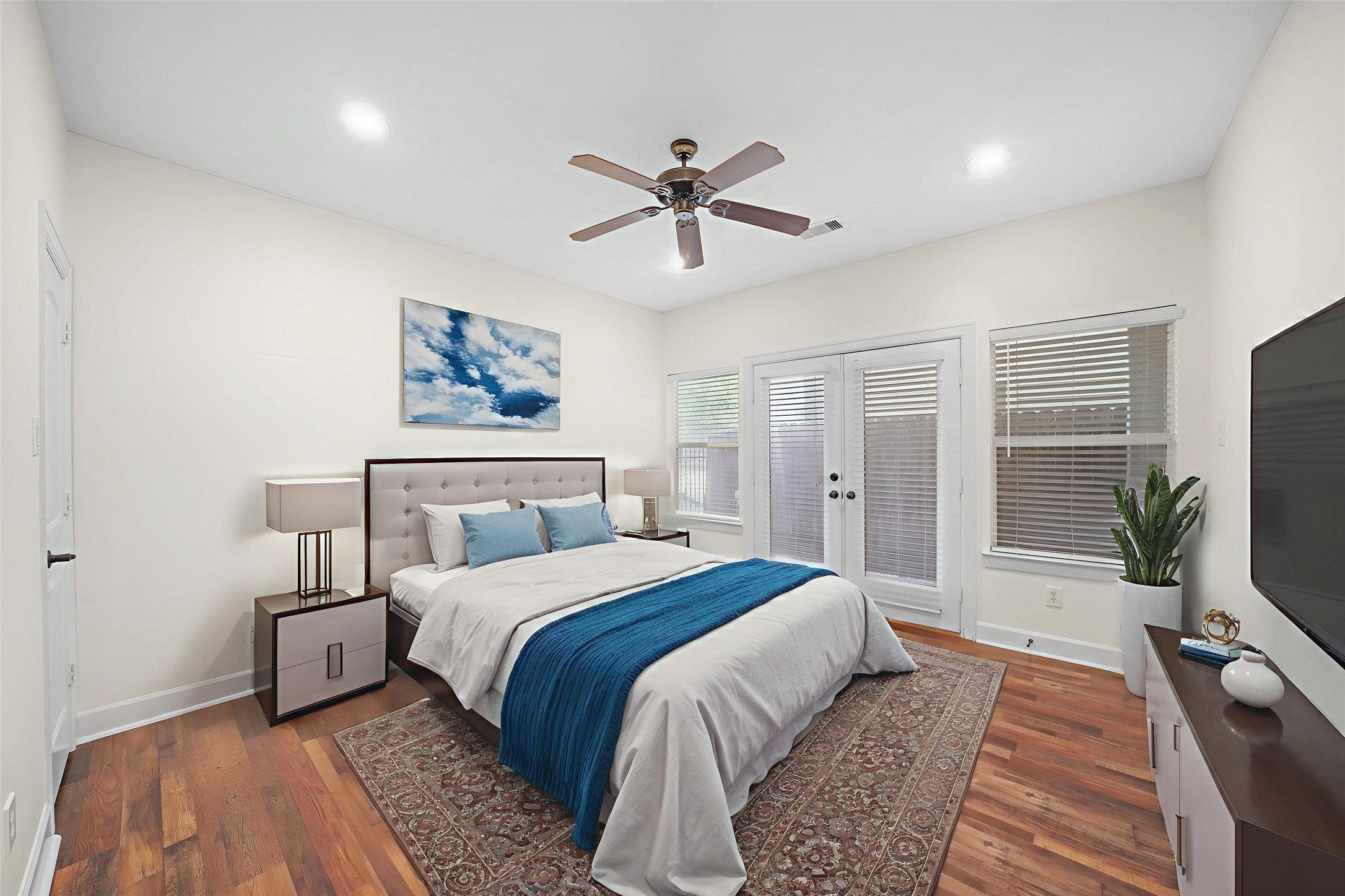 Virtually Staged: Secondary bedroom located on the first floor. It features hardwood floors, windows with privacy blinds, a ceiling fan, and a double glass door with immediate access to the backyard.