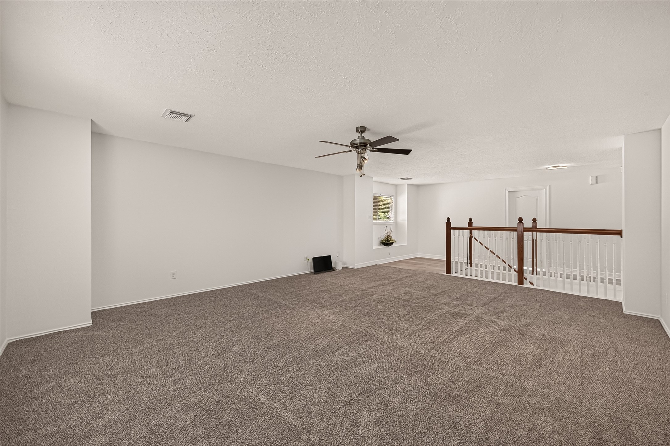 The upstairs game room offers plenty of room for movie nights, games, or a second living area, with an open view toward the staircase.