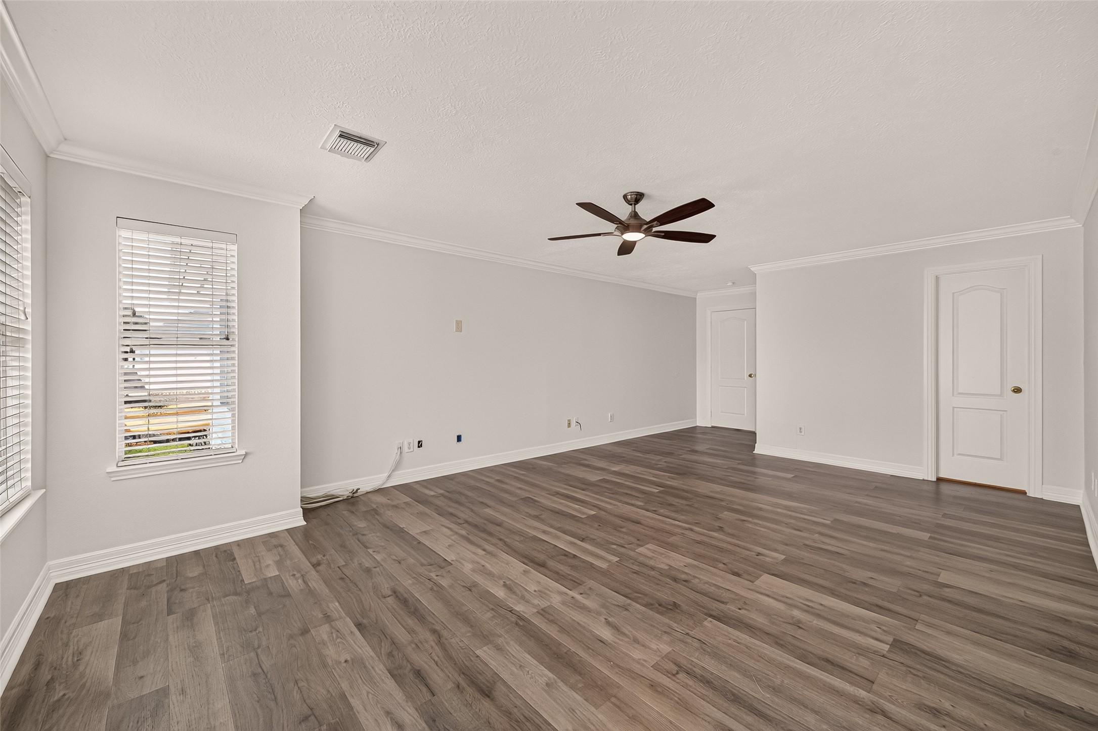 Natural light, and vinyl flooring give the spacious primary bedroom a bright, polished feel, with plenty of room for a king size bed