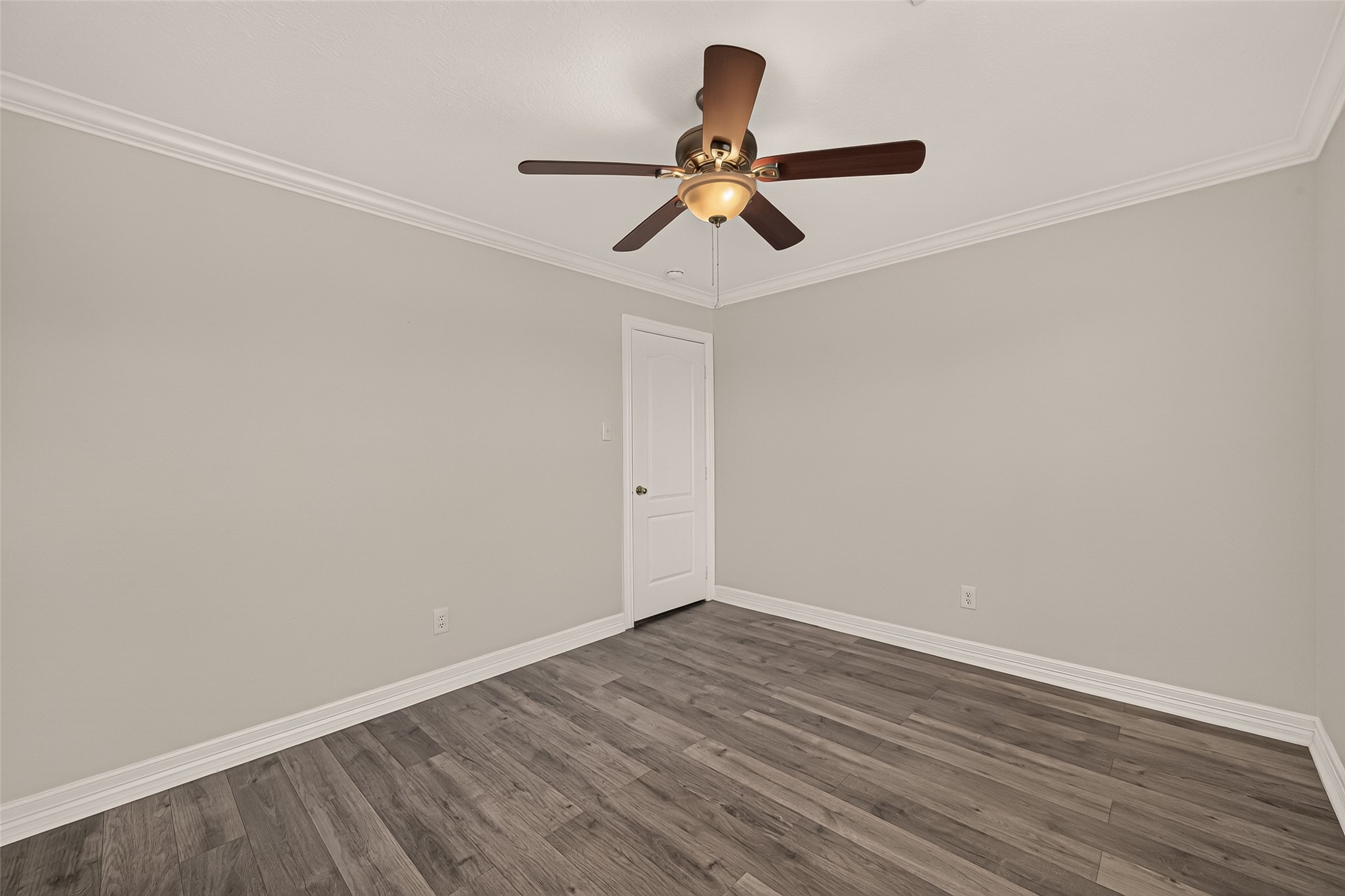 This second guest bedroom pairs vinyl flooring with crown molding and a ceiling fan, offering a clean slate for a cozy retreat or home office.