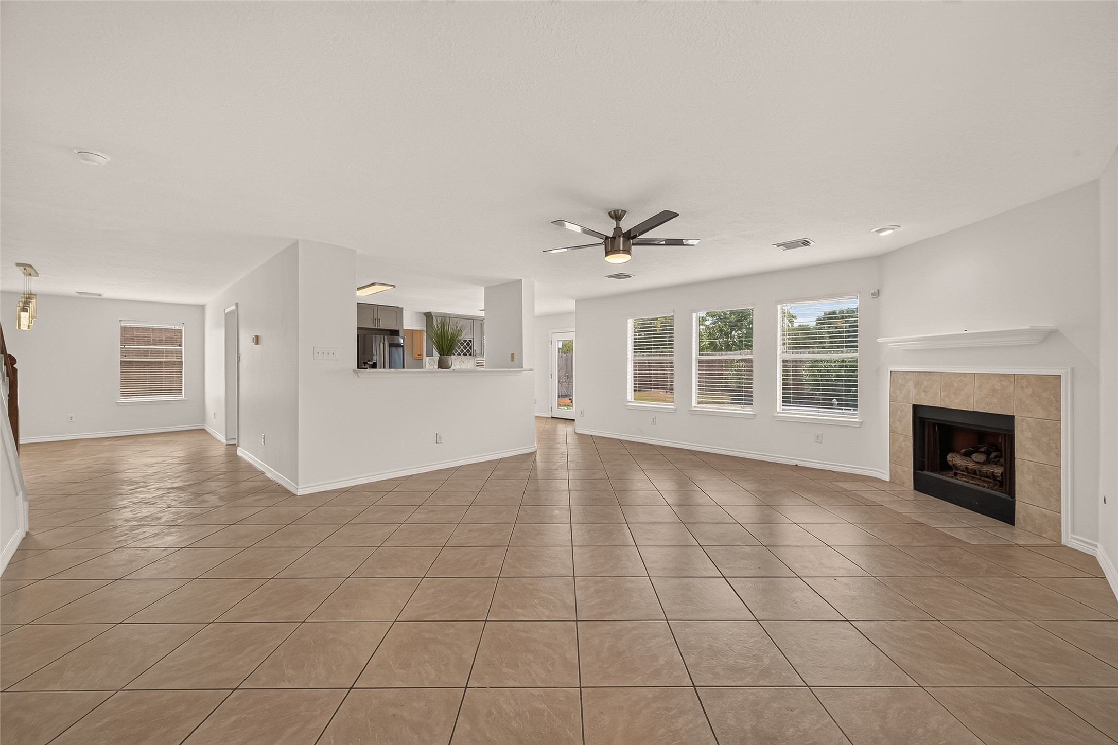 A wide view of the main floor shows how the dining area, kitchen, and family room connect, with a breakfast bar overlooking the fireplace and backyard windows.
