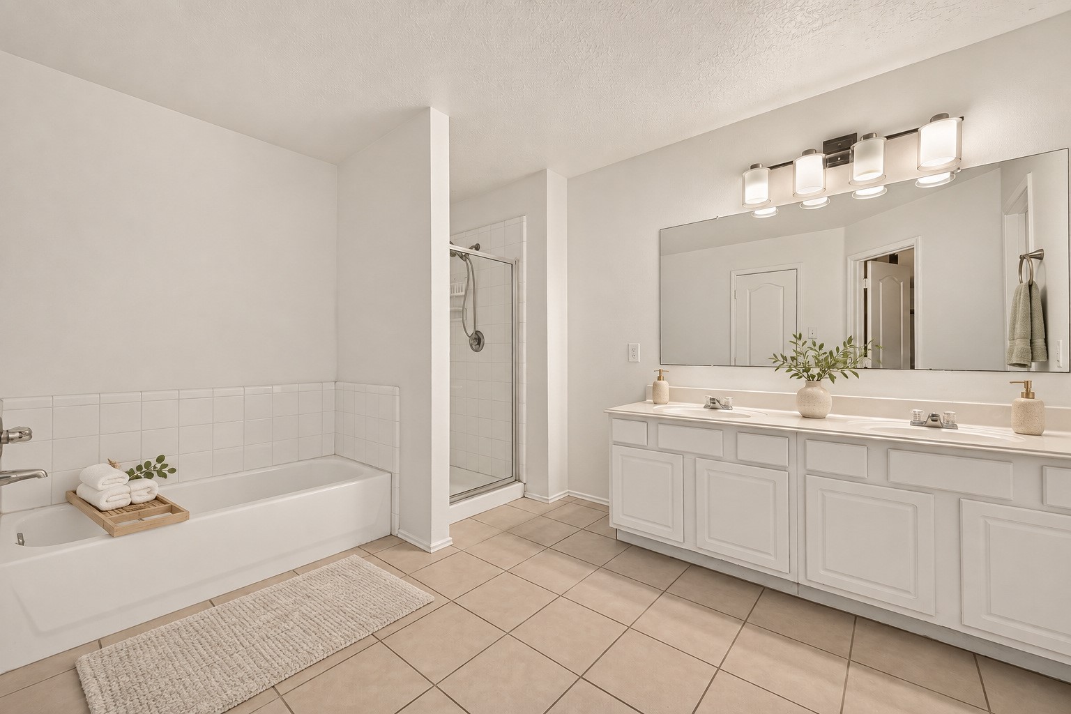 The primary bathroom features a double vanity, soaking tub, and separate glass-enclosed shower. Virtually staged.