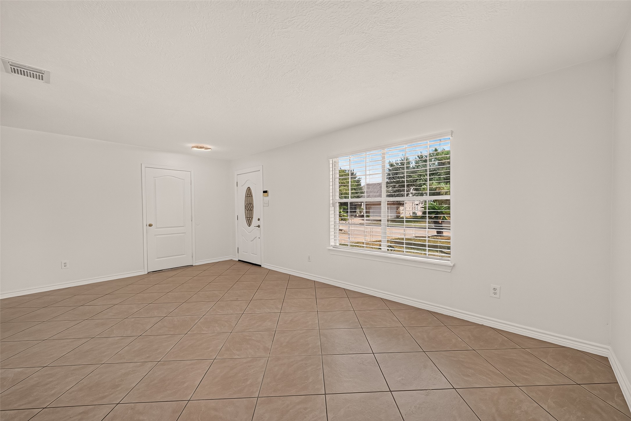 Step inside a welcoming living room where a large front window brings in natural light and tile flooring offers easy everyday living.