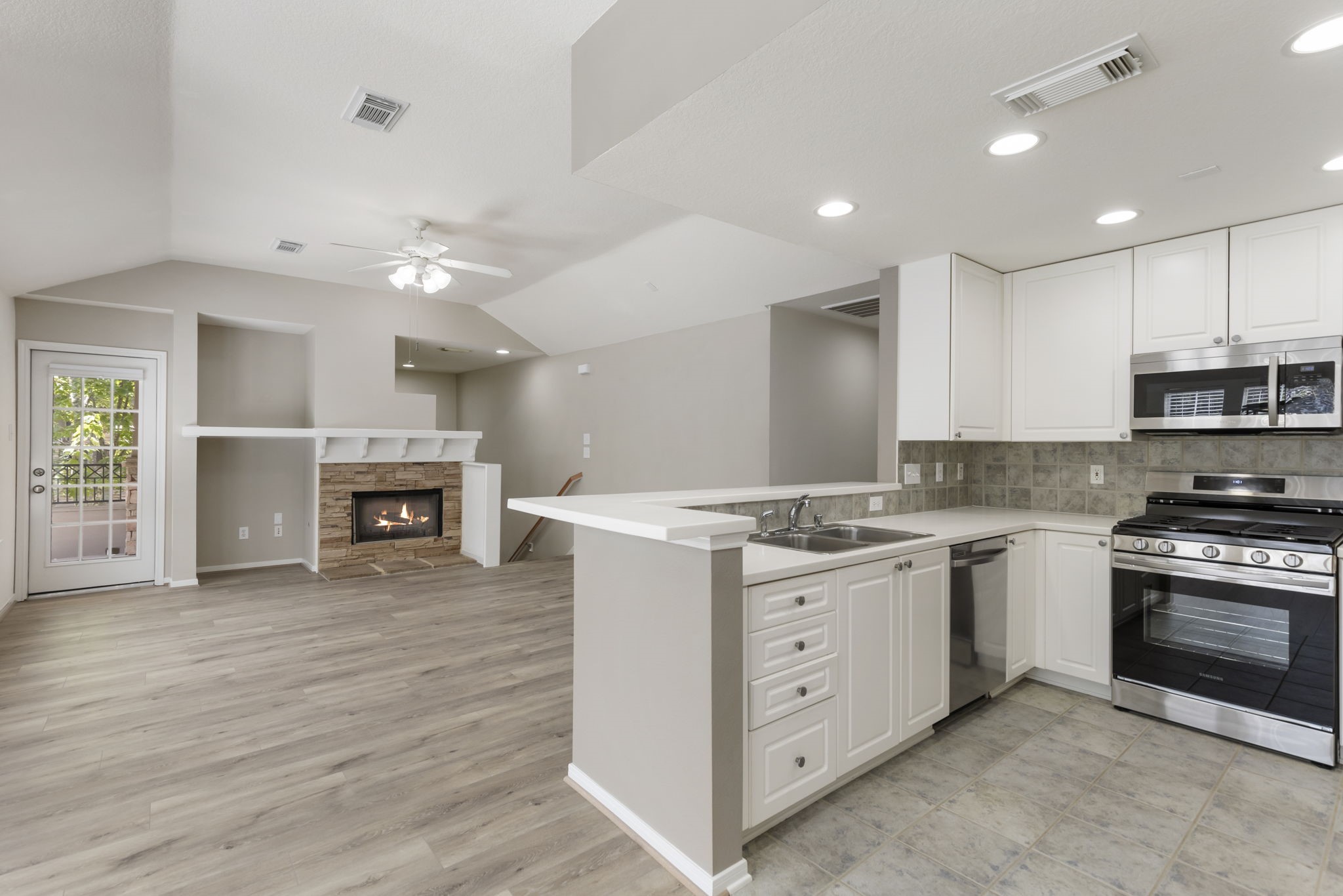 Stainless steel appliances including refrigerator and a gas range.