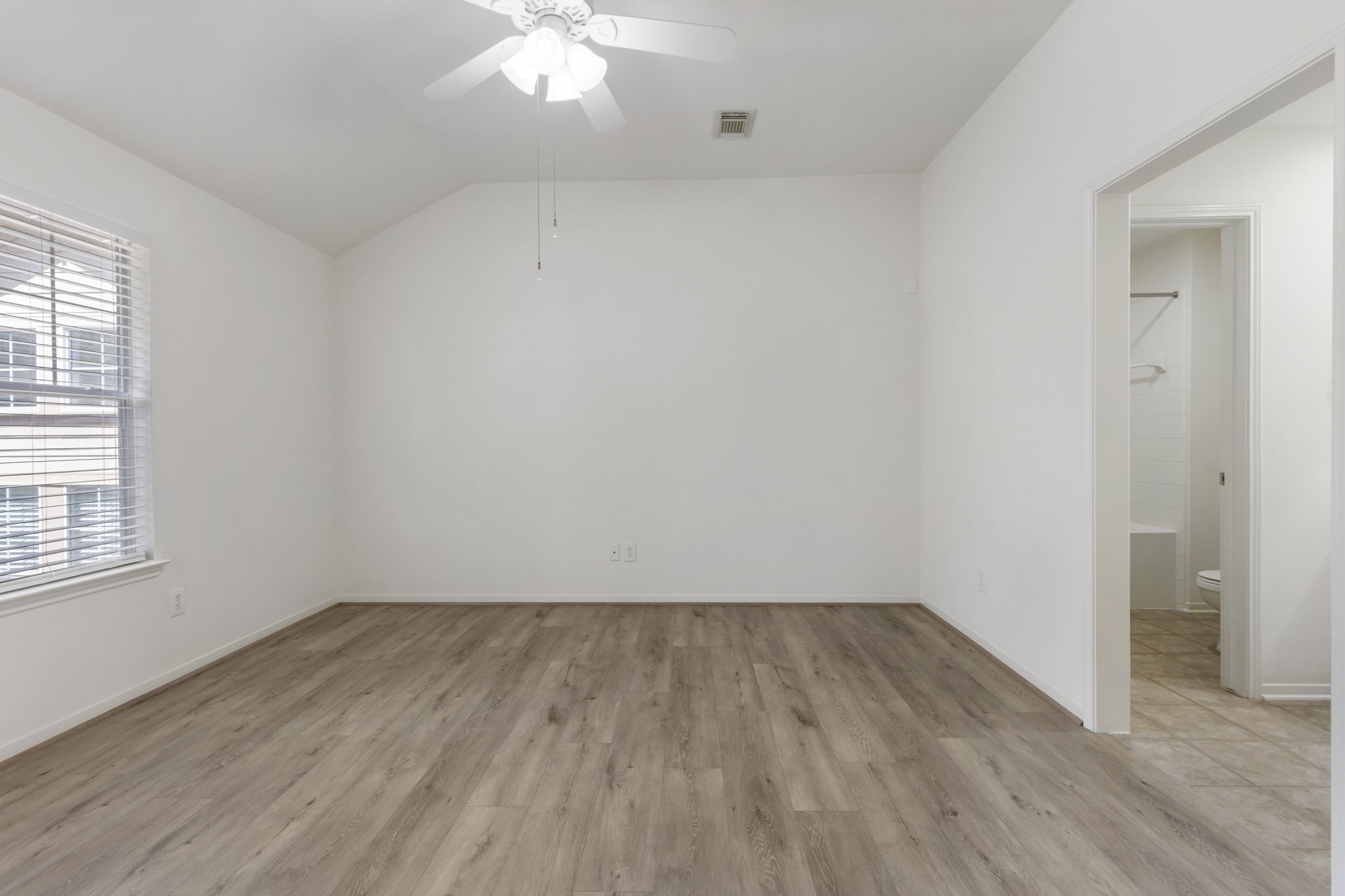 Primary bedroom with ensuite bath, spacious closet, and ceiling fan.