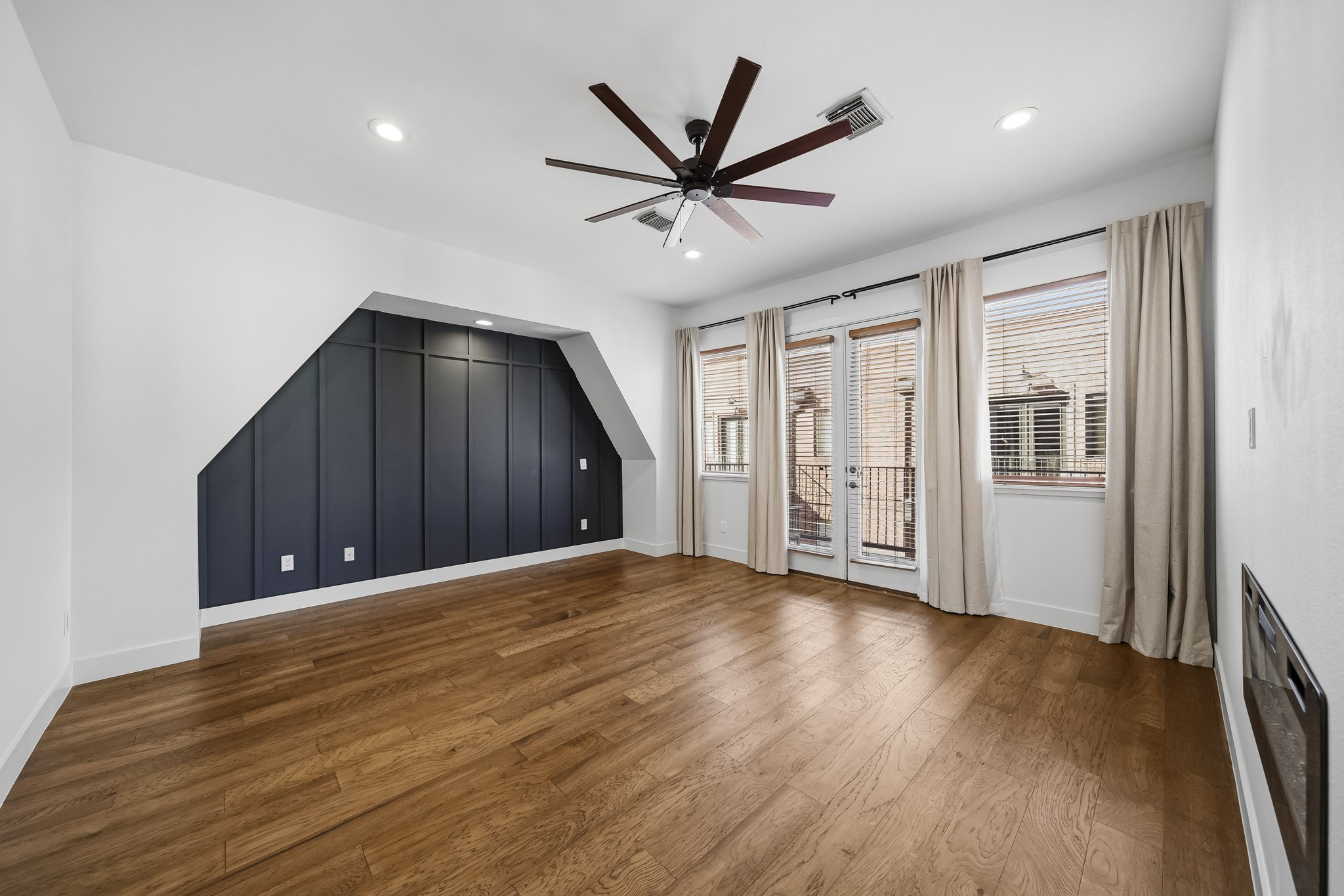 The third-floor primary suite offers a luxurious private retreat, featuring rich hardwood floors, newly installed recessed lighting and a ceiling fan. Elegant picture-frame molding creates a striking accent wall, adding architectural character and sophistication to this beautifully appointed space.