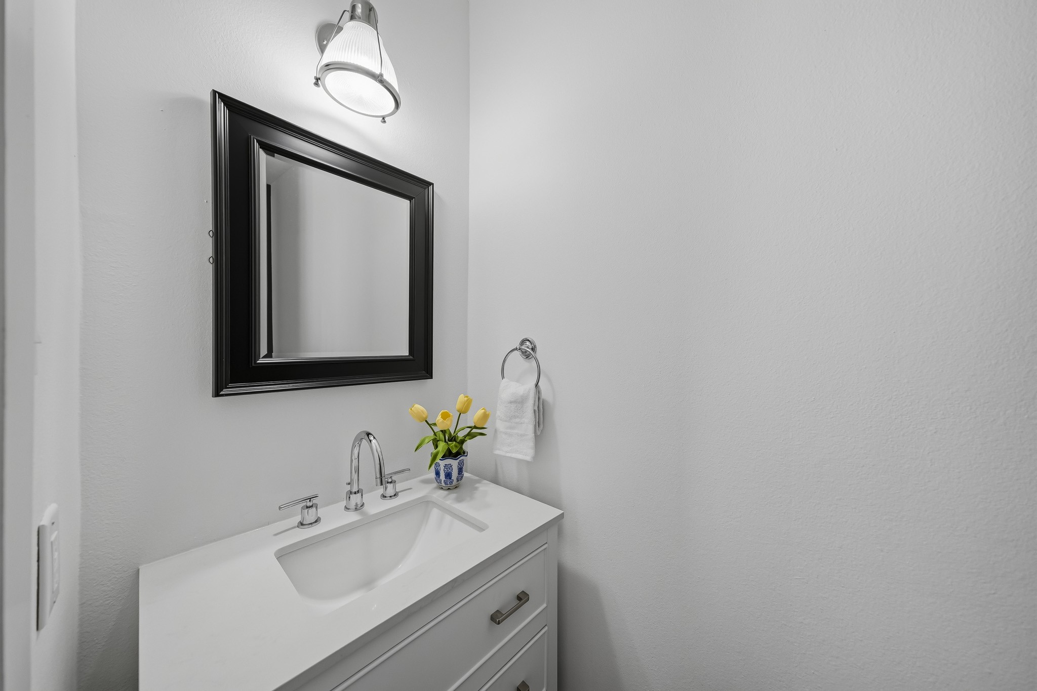 The elegantly appointed powder room features rich hardwood floors, a furniture-style vanity installed in 2023 and topped with a Quartz counter and a distinctive wood beadboard accent wall that adds warmth and architectural character.
