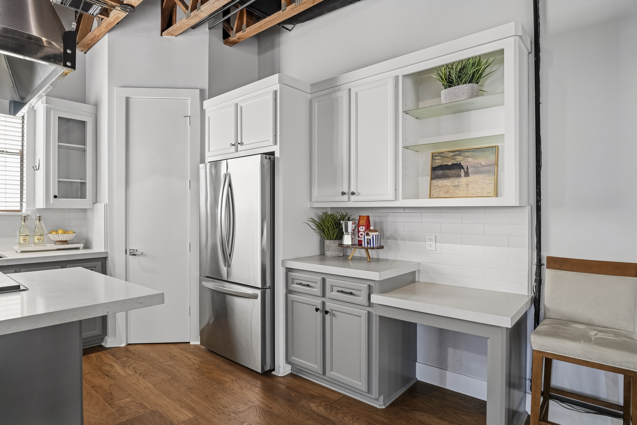 A beautifully appointed desk area and butlers pantry combine style and functionality, featuring a classic subway tile backsplash installed in 2023, built-in cabinetry, and elegant glass shelving for displaying fine glassware and decorative accents. This versatile space offers additional storage and a convenient area for organization.