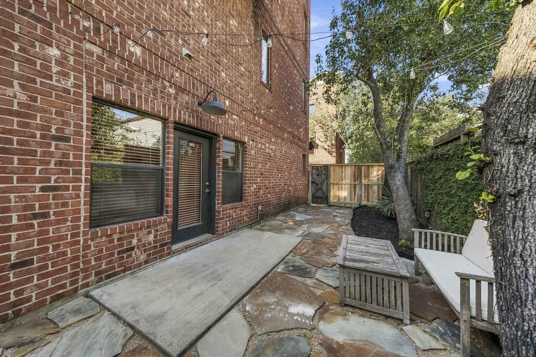 A private side patio features a concrete surface framed by flagstone pavers, creating a charming outdoor space to enjoy fresh air and relaxation.