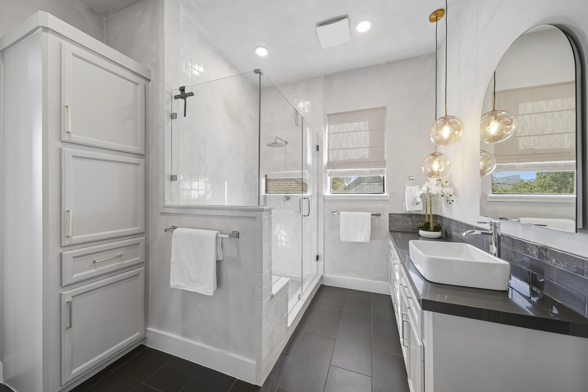 The luxurious walk-in shower features a sleek frameless glass entry, floor-to-ceiling tile surround, a rainfall showerhead and a quartz-topped bench, creating a spa-inspired experience in the comfort of your own home.