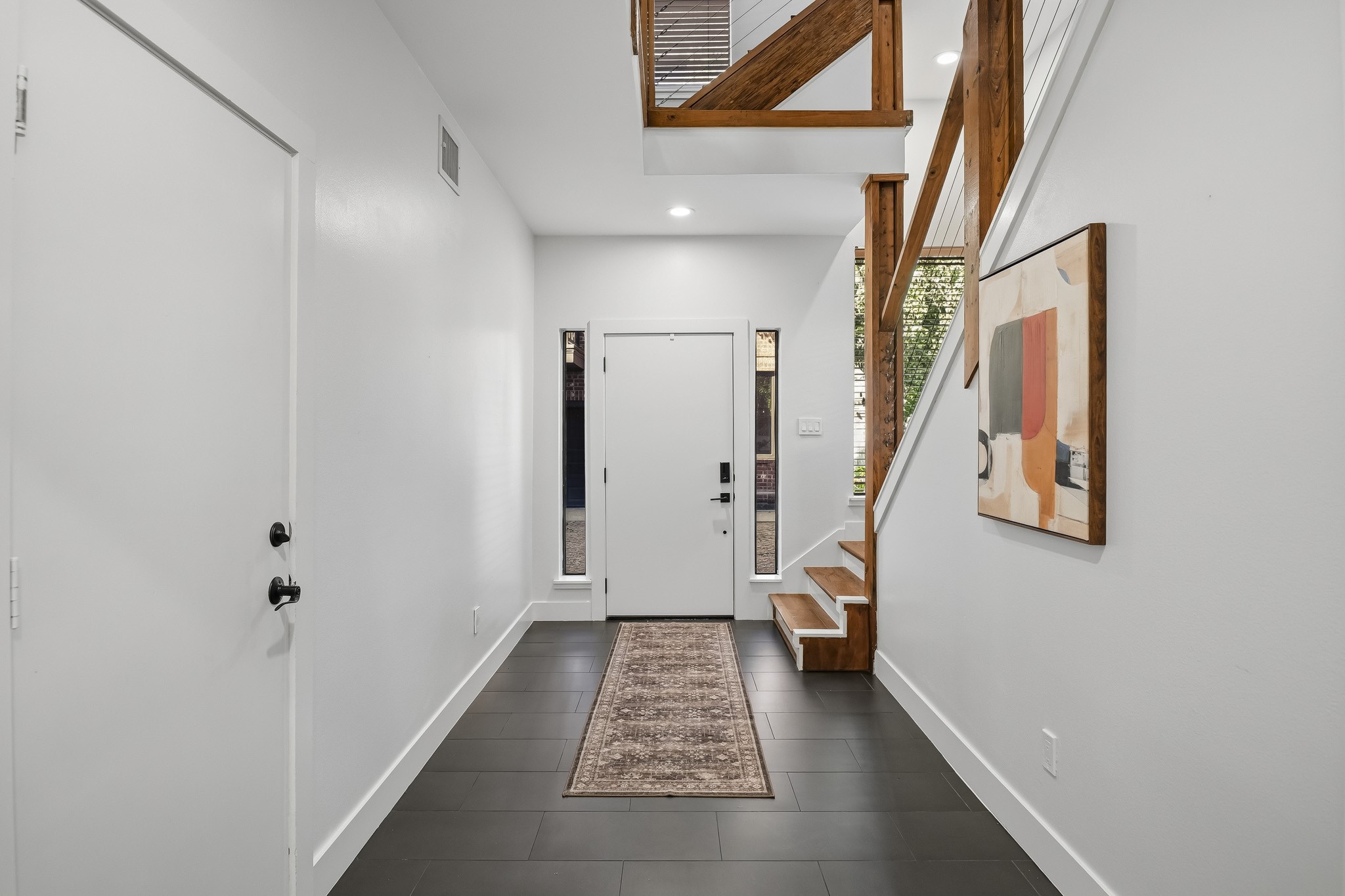 Another view of the entry with the garage entrance the the left and a nearby storage closet under the stairs.