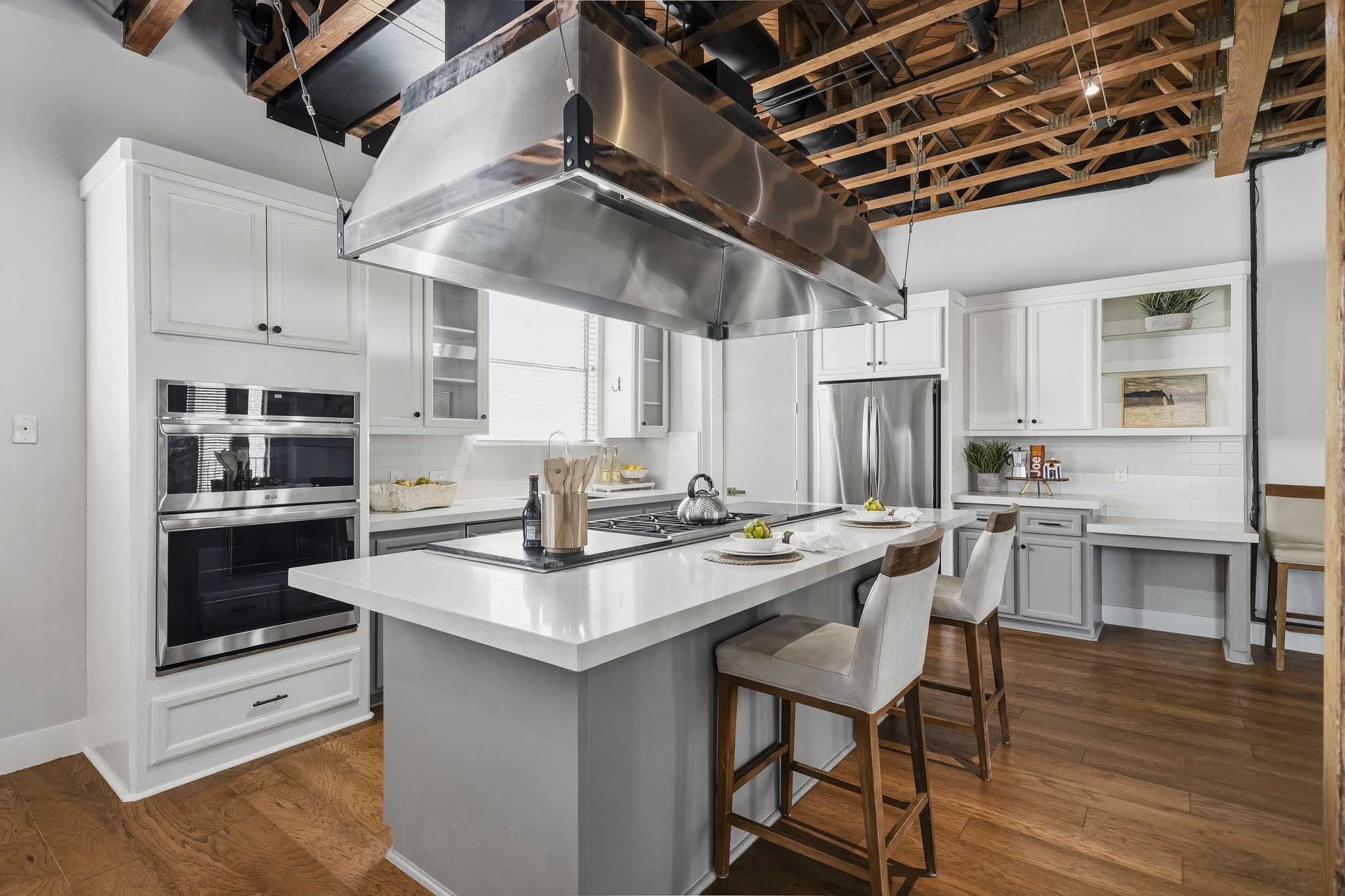 The beautifully appointed kitchen is anchored by an impressive 10-foot island topped with elegant Quartz countertops. A professional-grade six-burner Wolf cooktop and commercial-style ventilation hood creates a chef-inspired setting that combines exceptional culinary performance with sophisticated design.