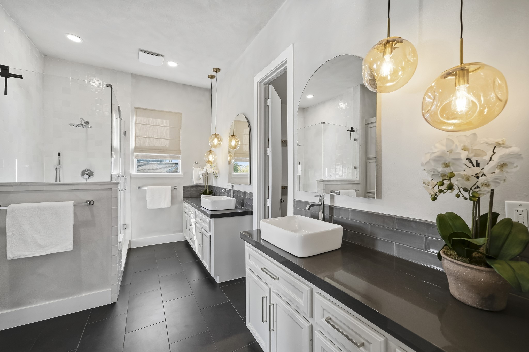 Elegant decorative lighting complements recessed illumination, casting a warm glow across the space, while expansive 12 x 24 tile flooring adds a sophisticated, cohesive finish throughout.