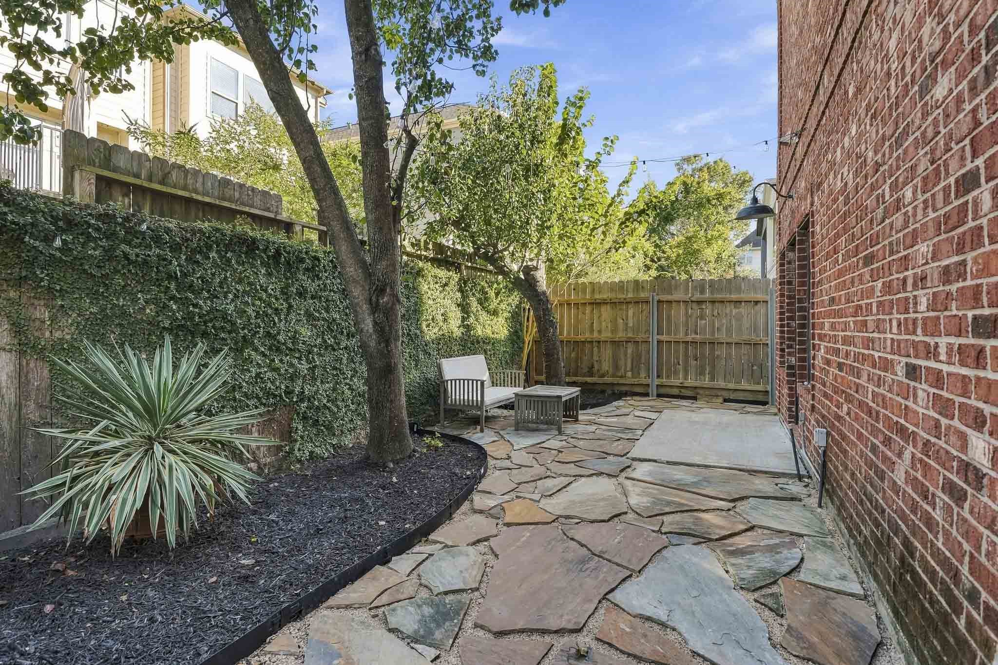 Mature shade trees and the patio adorned with string lights creates a charming outdoor ambiance, offering a beautiful setting for relaxing beneath the canopy or enjoying evenings under the stars.