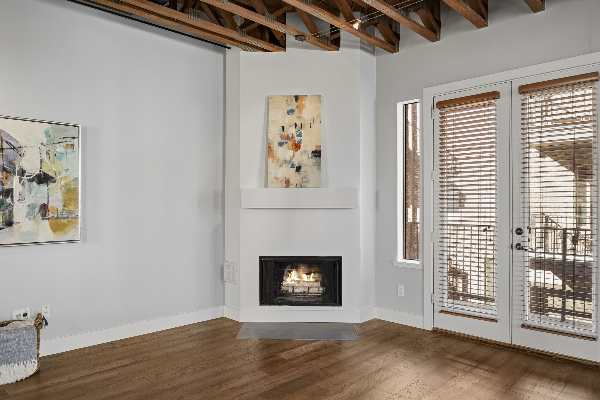 A classic wood-burning fireplace, accented by a wood mantel, creates a striking focal point, while exposed beams and architectural wood trusses lend rich character, timeless charm and an inviting sense of warmth to the space.