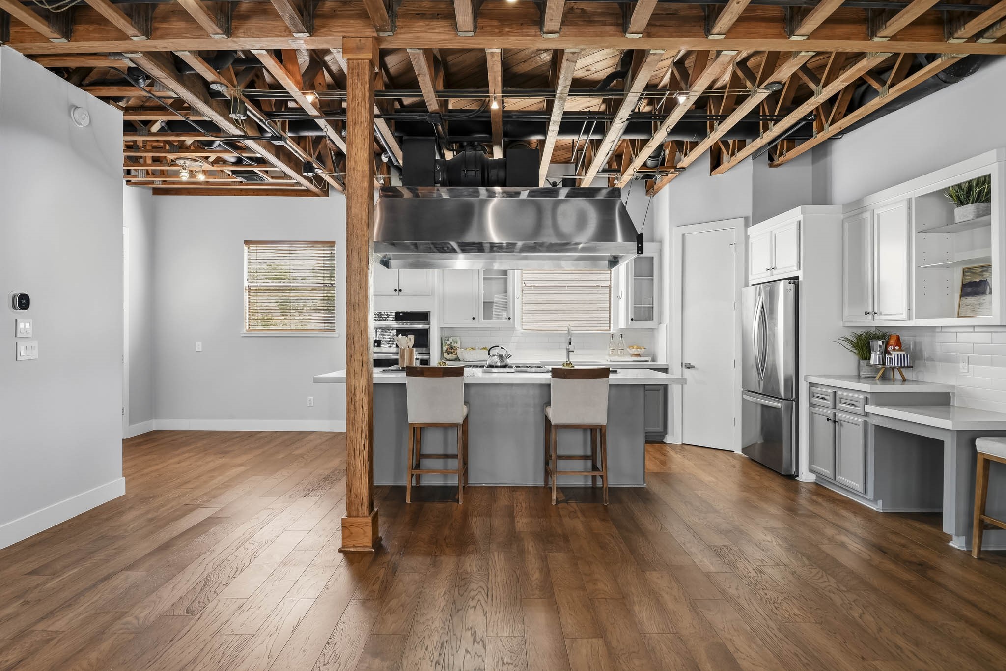 The inviting breakfast bar features rich hardwood floors and windows that welcomes natural light, creating a warm and comfortable setting for casual dining and leisurely mornings.
