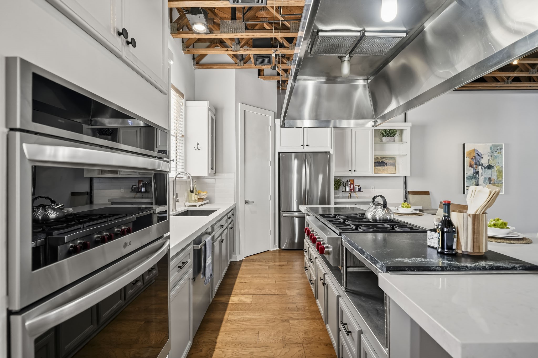 The beautifully appointed kitchen showcases Quartz countertops, a deep basin sink, classic subway tile backsplash, and cabinetry accented by elegant glass-front display doors. A premium appliance package includes an LG double oven with convection cooking and a convection microwave installed in 2025, stainless steel dishwasher and a new French door refrigerator ('25) that conveys with the home.